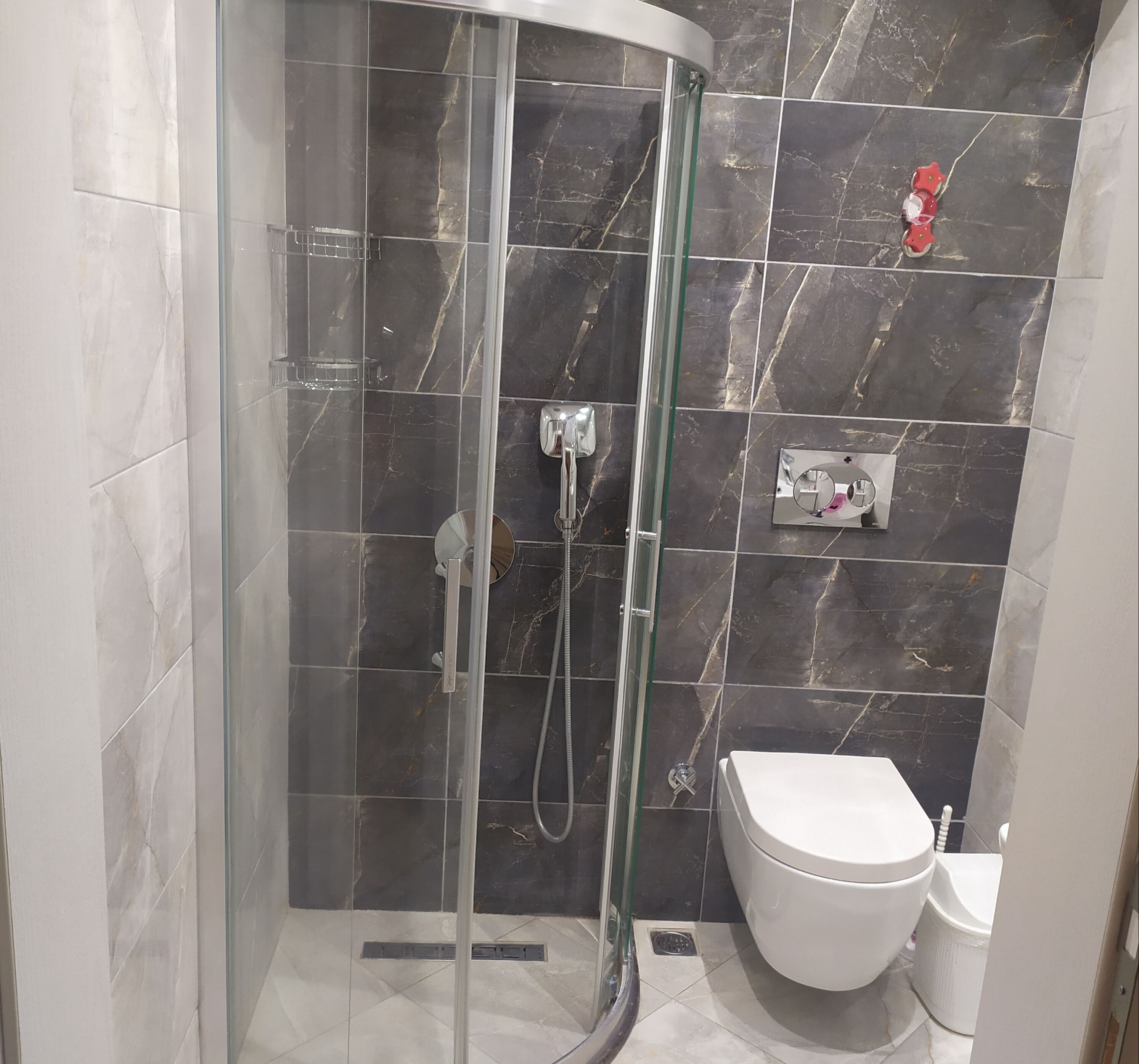 A bathroom with a glass-enclosed shower, a toilet, and a sink.