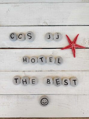 Une surface en bois sur laquelle sont inscrites en lettres les mots « HOTEL THE BEST » et une étoile de mer rouge.