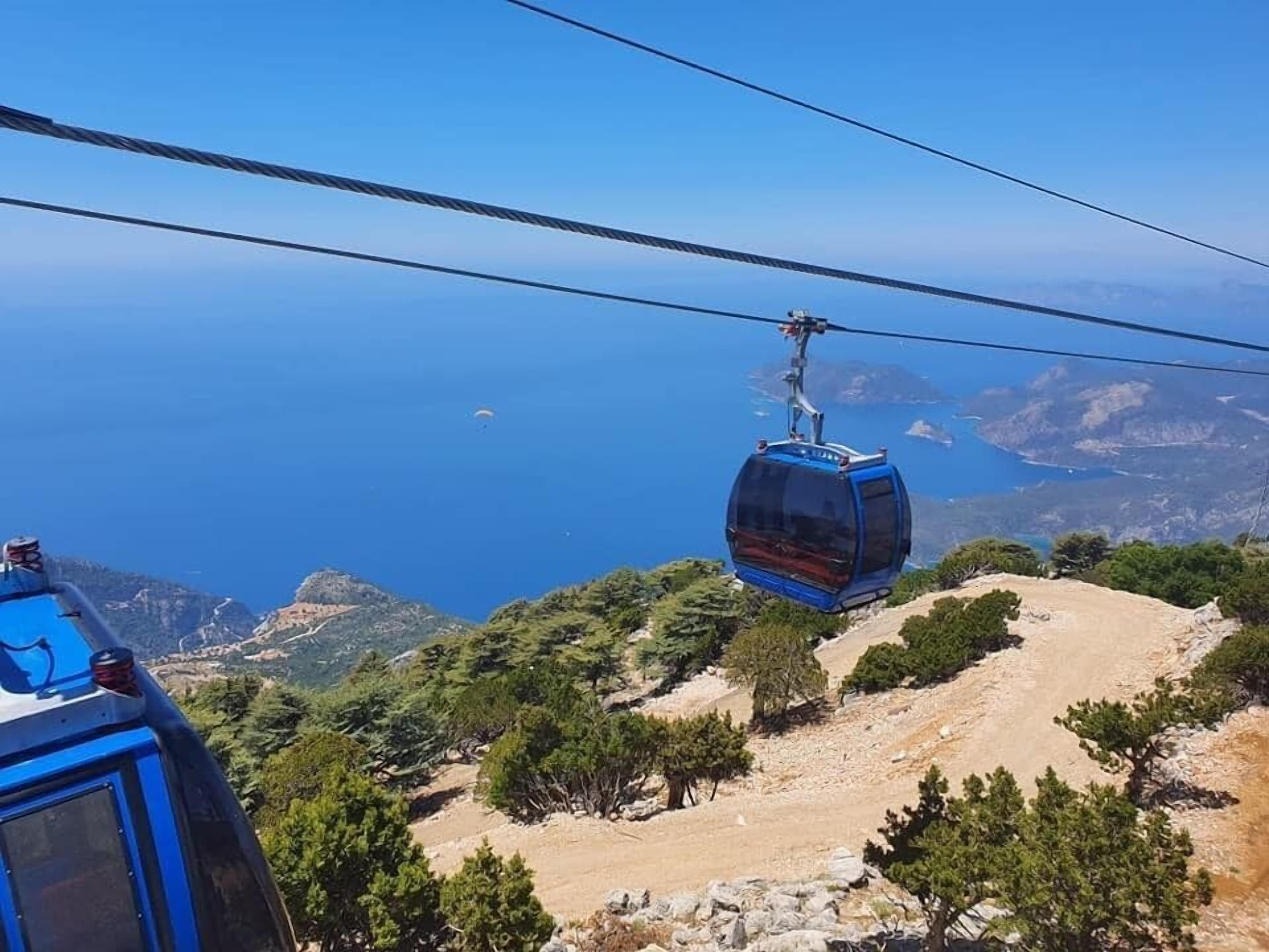 A cable car system with a clear view of the surrounding landscape, including trees and distant landforms.