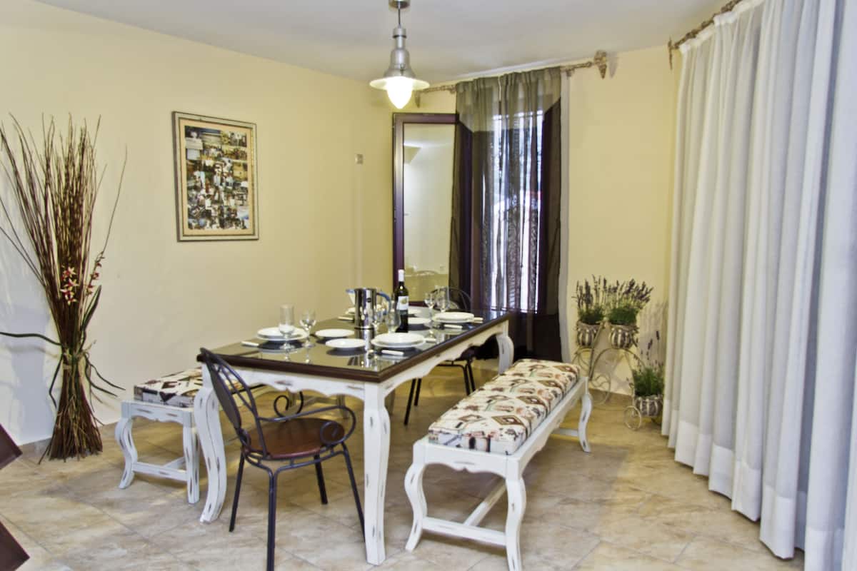 Un comedor con una mesa larga, sillas, un banco y una planta en maceta.
