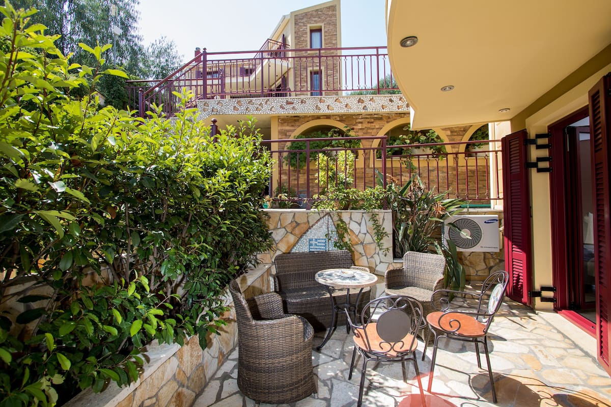 Un patio exterior con mobiliario de mimbre y una pared de piedra.