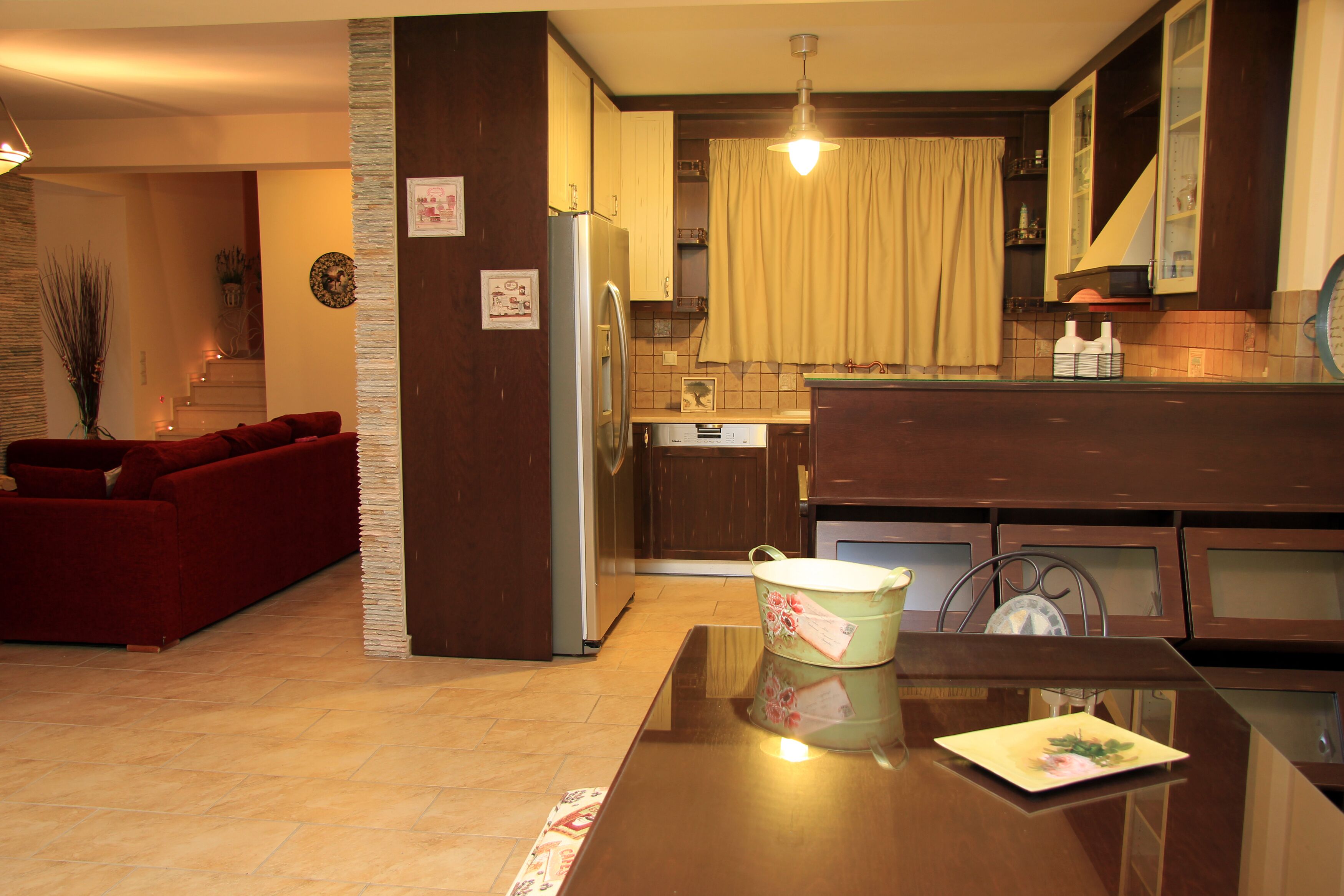 Un espacio habitable compacto con área de cocina, una mesa de comedor con un objeto decorativo, un sofá y una escalera que conduce a un nivel superior.