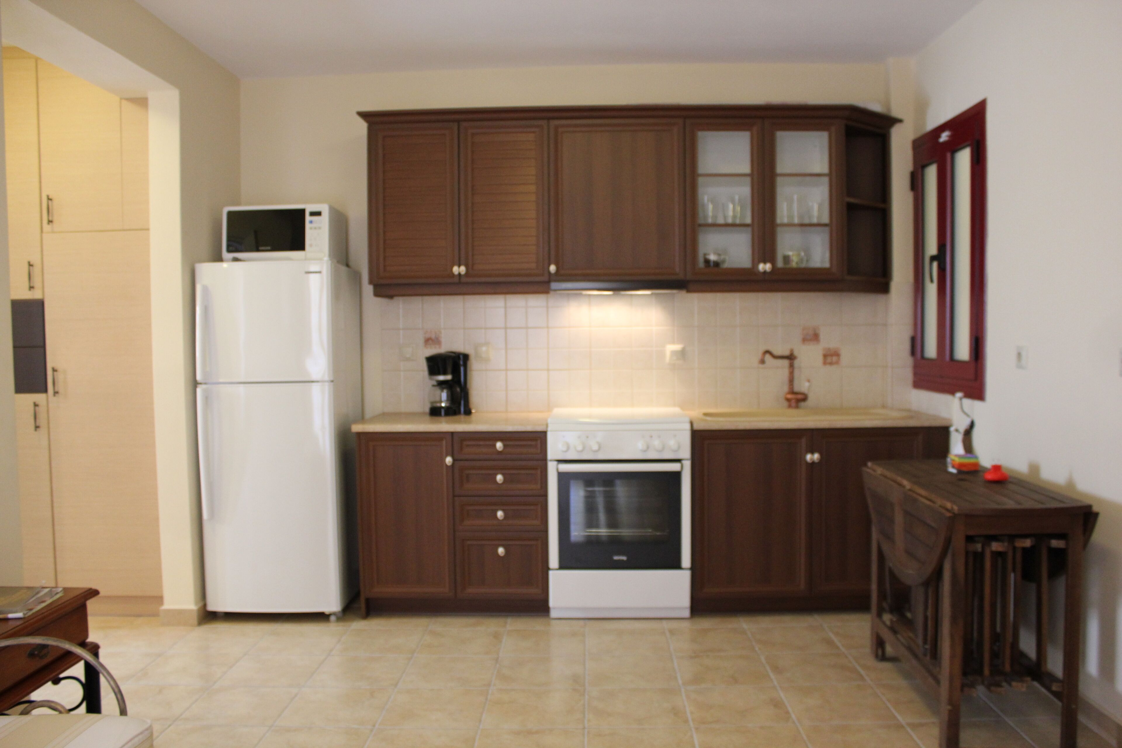 A compact kitchen with wooden cabinets, a white refrigerator, a stove, and a coffee maker.