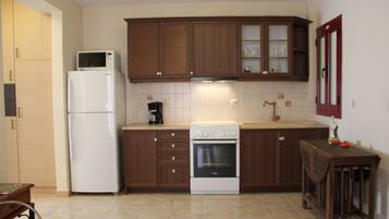 A compact kitchen with wooden cabinets, a white refrigerator, a stove, and a coffee maker.