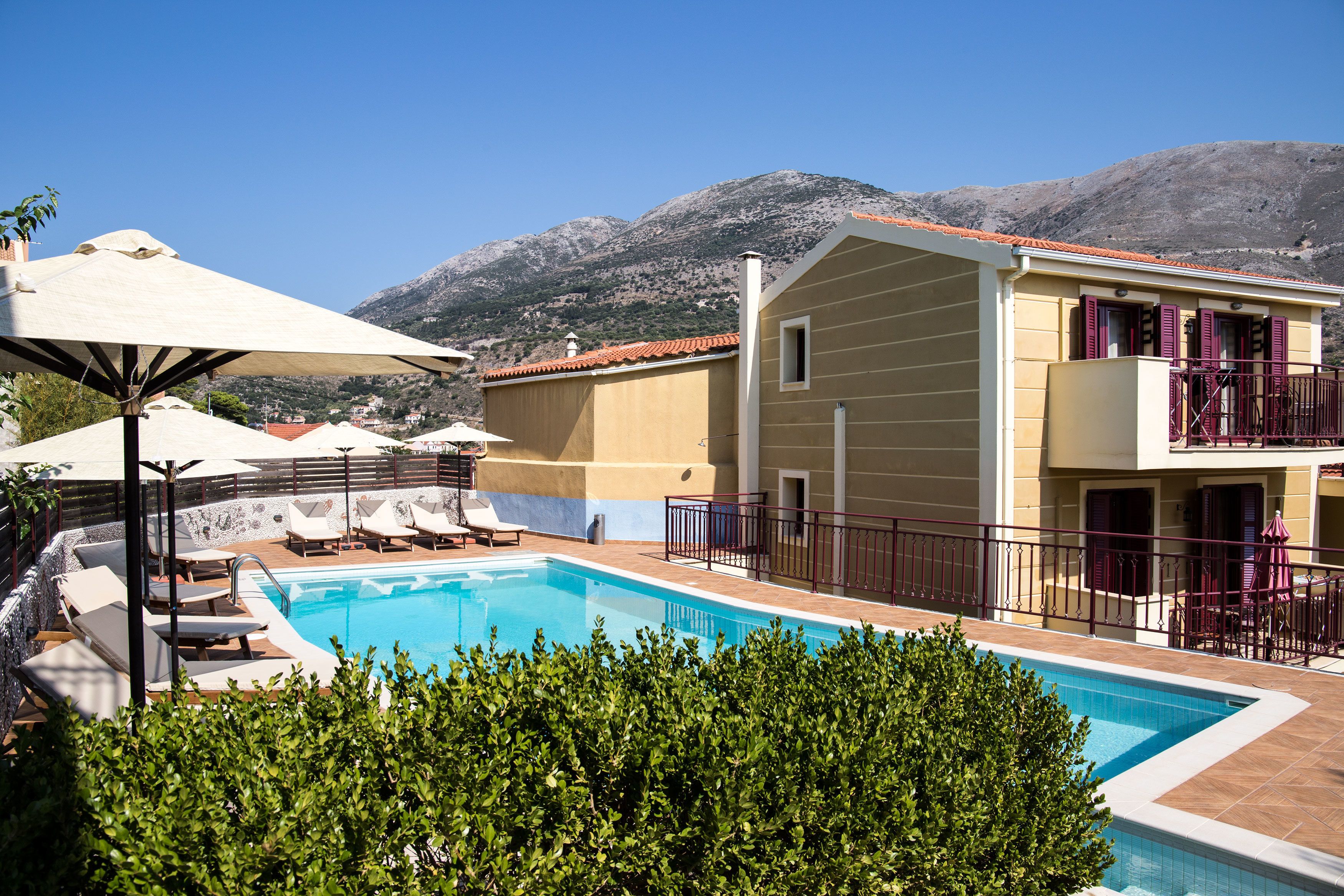 A pool area with lounge chairs, a small pool, and a building with balconies.