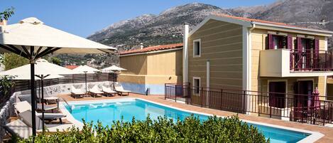 A pool area with lounge chairs, a small pool, and a building with balconies.