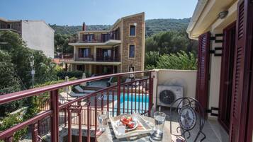 Un balcón con piscina, mobiliario de exterior y una mesa de comedor con comida.