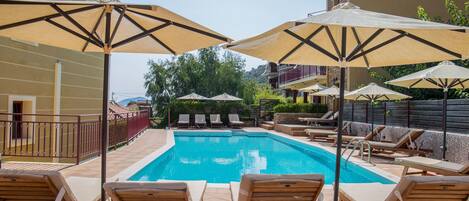 En säsongsöppen utomhuspool, parasoller och solstolar