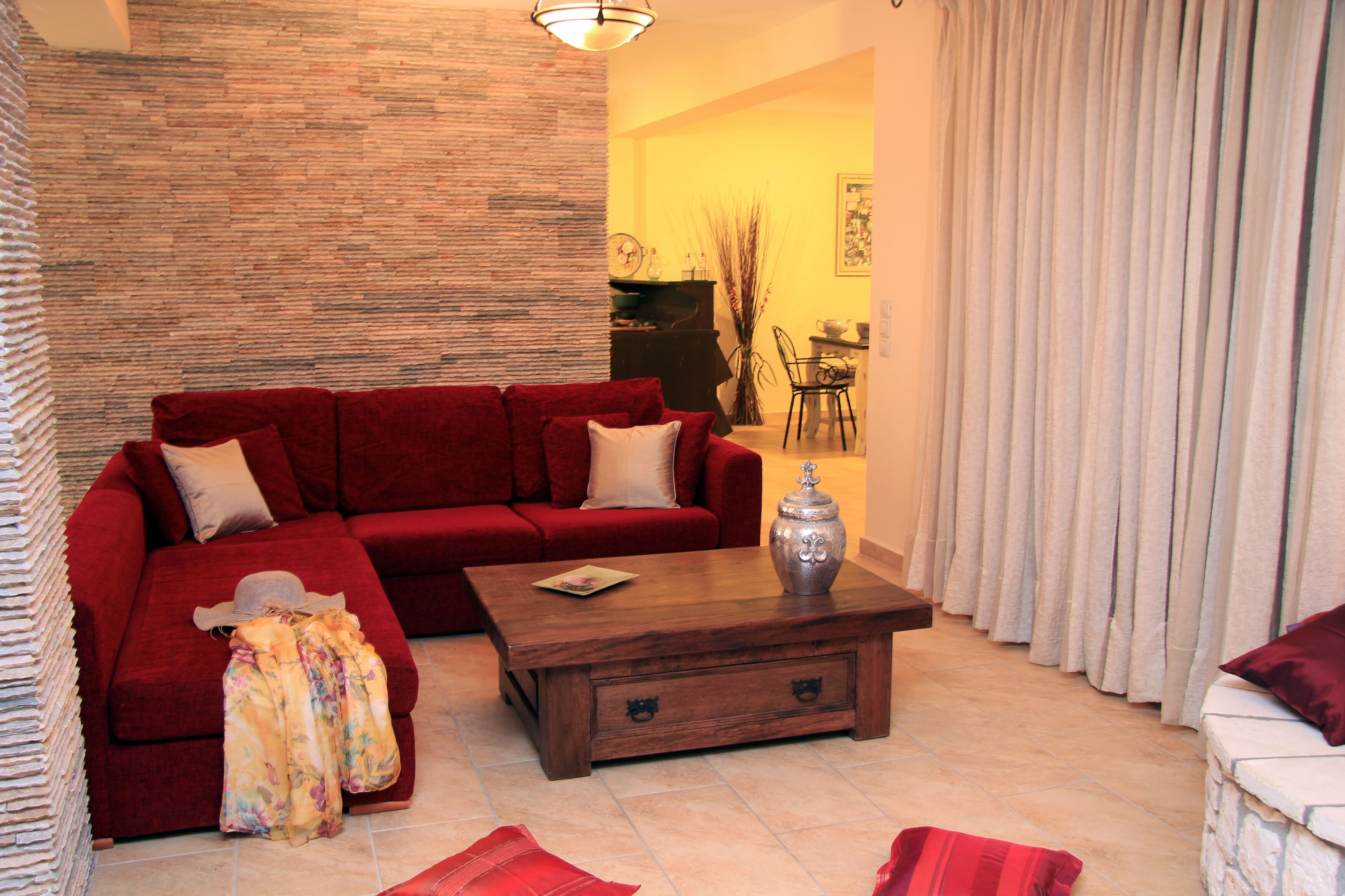 A living room with a red sofa, a wooden coffee table, and a patterned throw blanket.