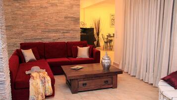 A living room with a red sofa, a wooden coffee table, and a patterned throw blanket.