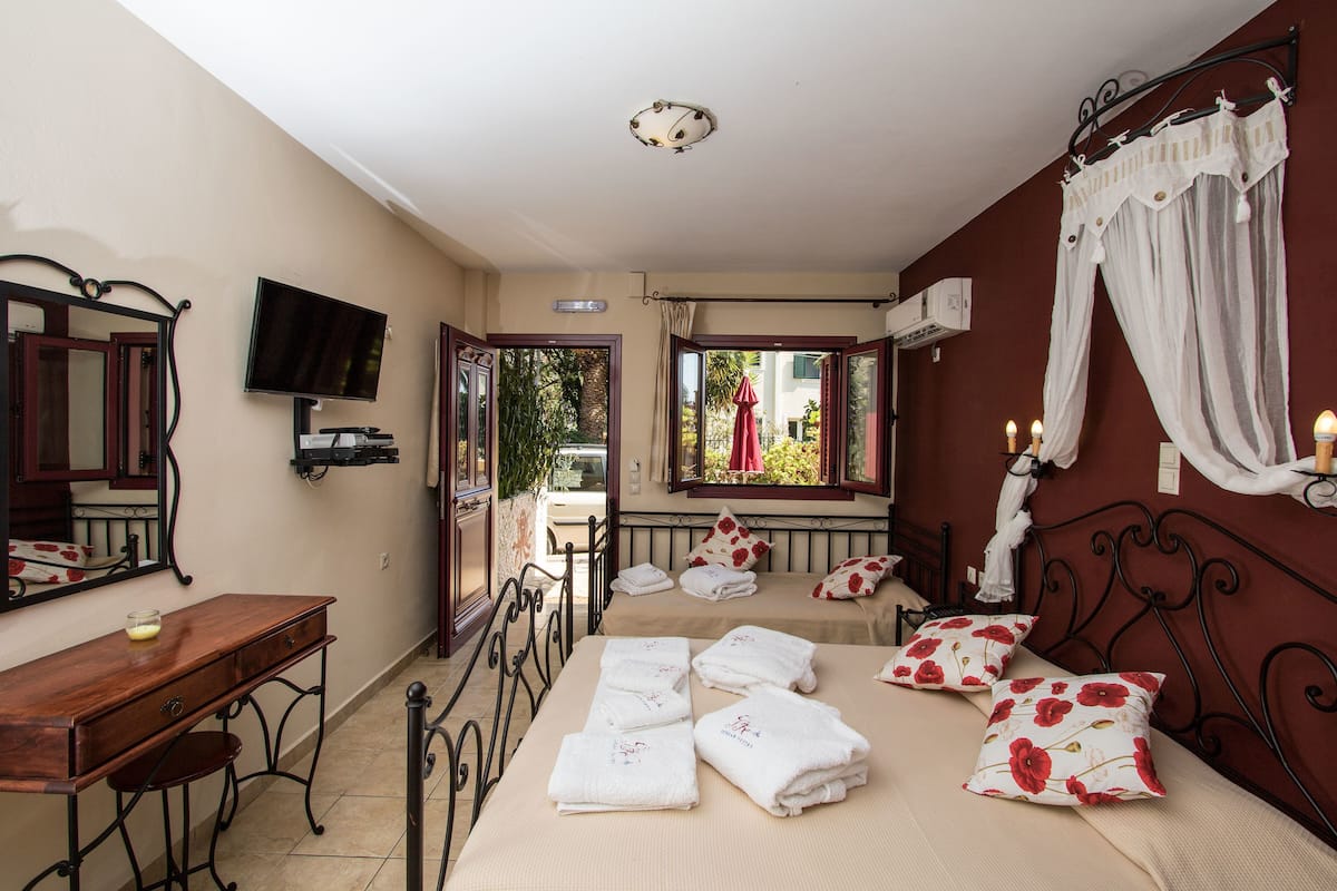 Un dormitorio con cama, escritorio, televisor y ventana con cortinas.