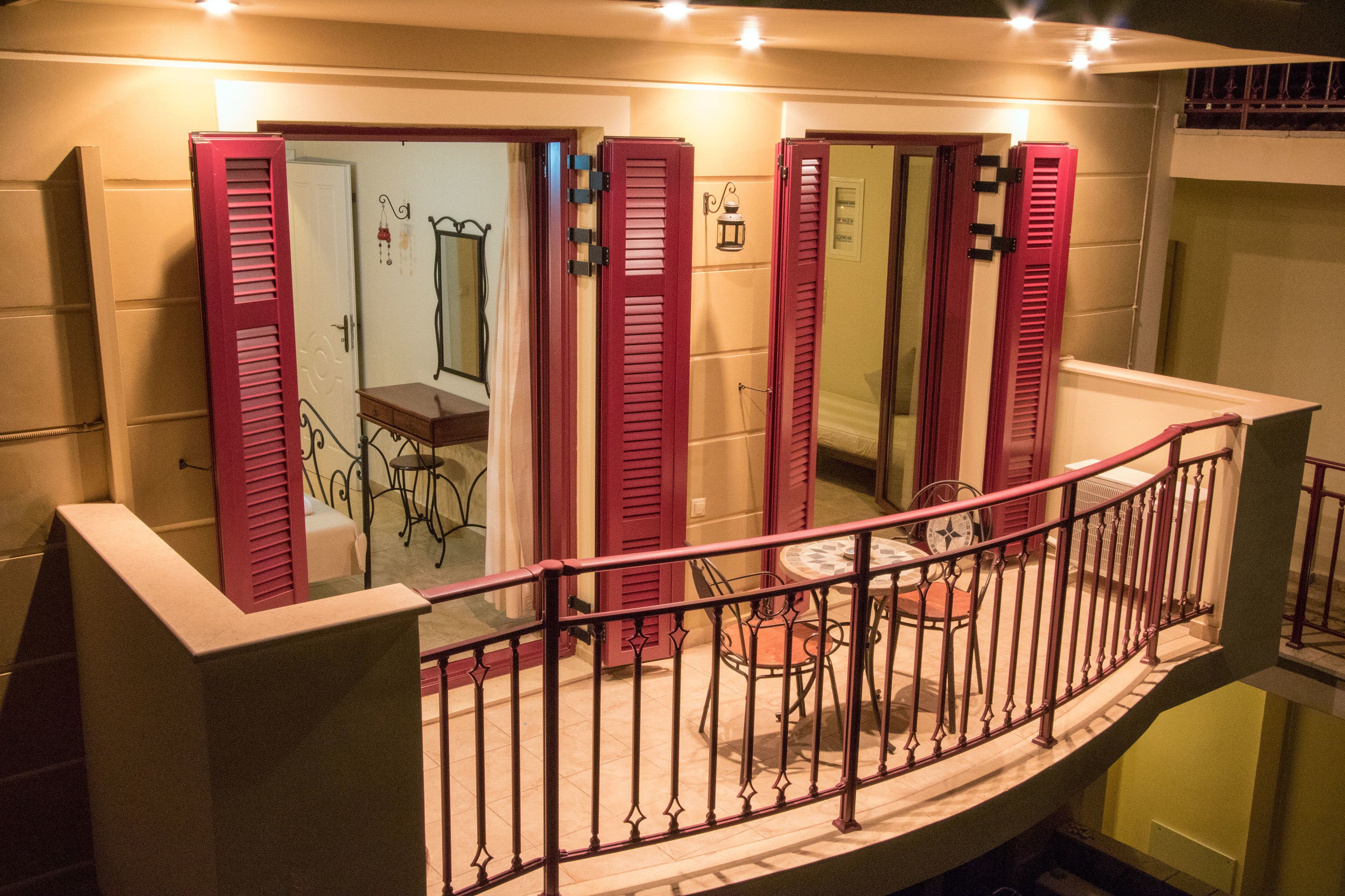 A balcony with a wrought iron railing, a small table, and chairs.