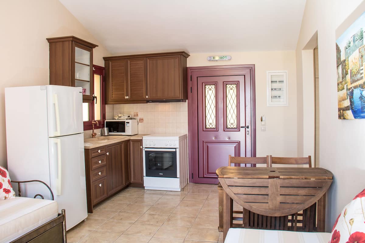 Una cocina compacta con armarios de madera, un refrigerador blanco, una estufa y una mesa de comedor con sillas.