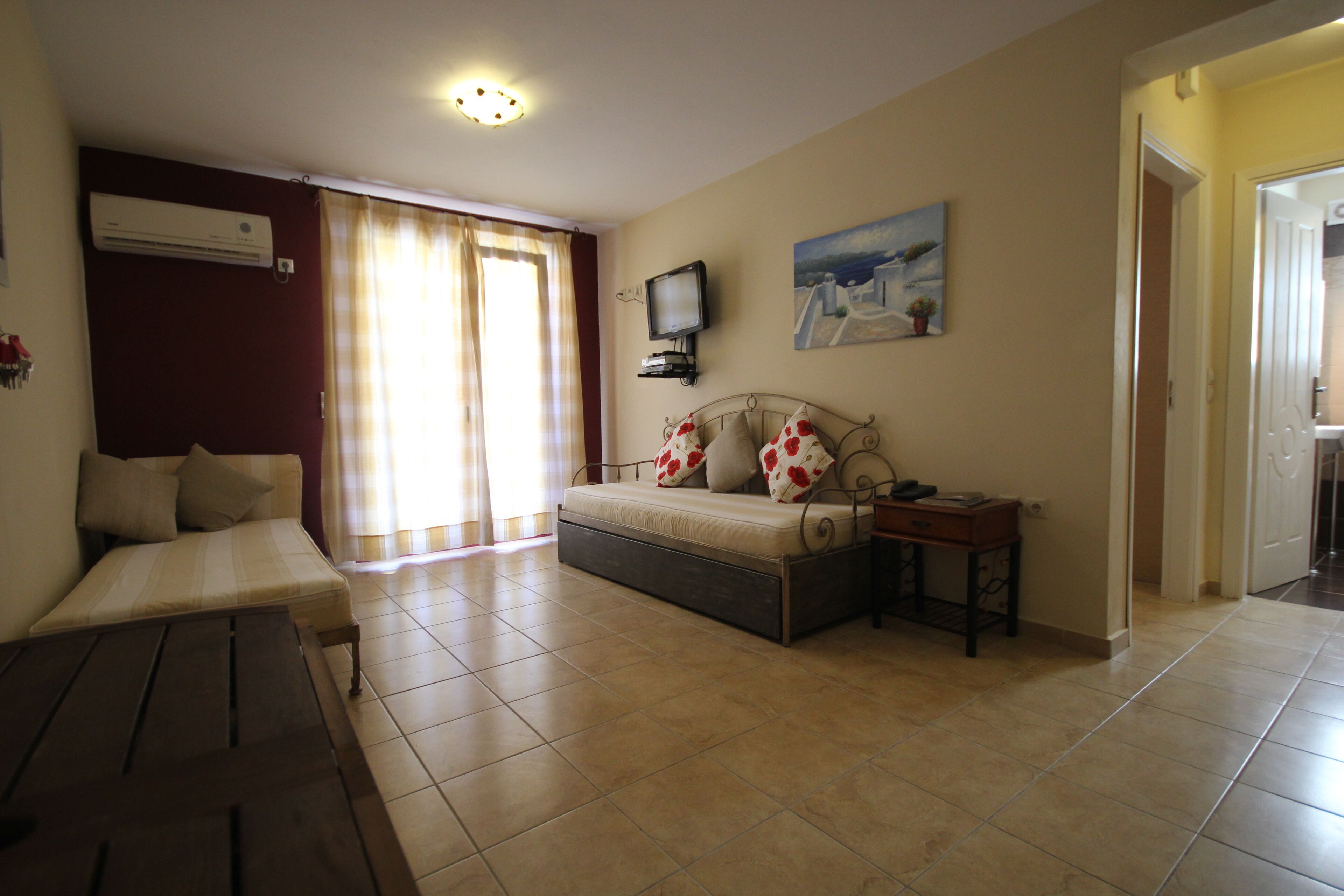 Una habitación con una cama, televisión, un cuadro y una ventana con cortinas.