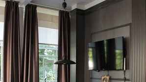 Una habitación con sofá, mesa, chimenea y televisor montado en la pared.