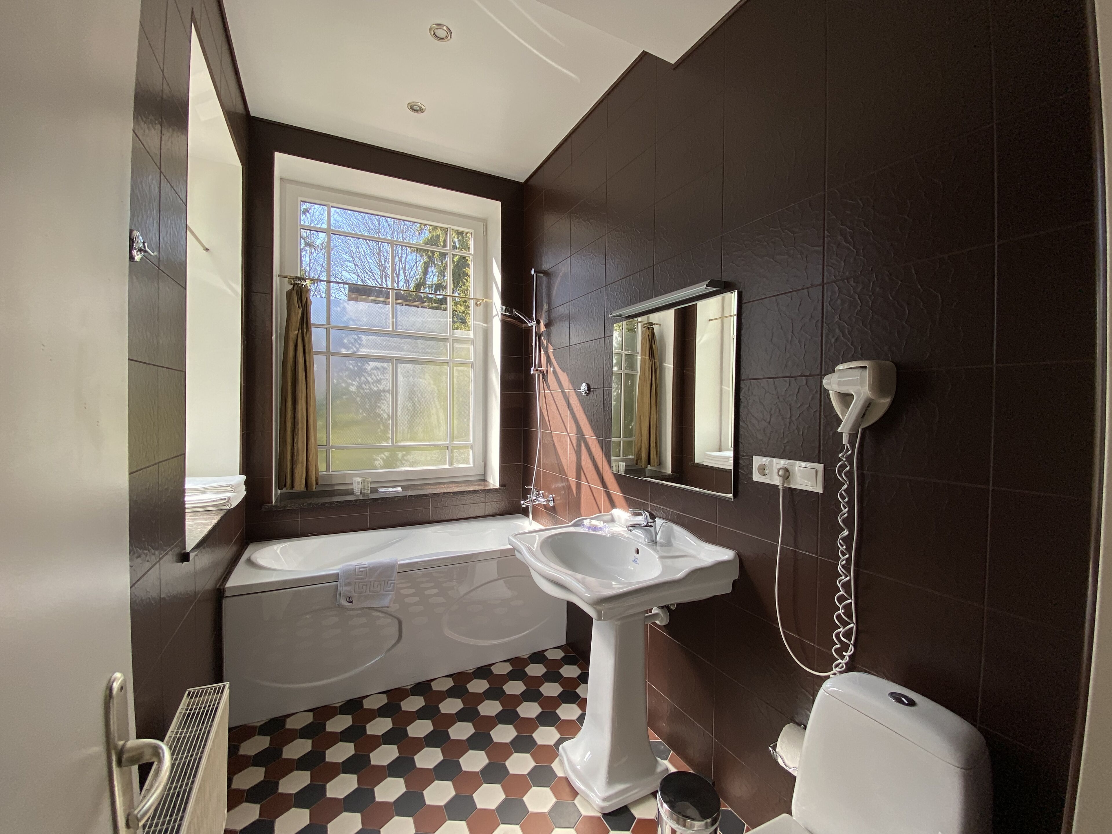 Baño con bañera, lavabo e inodoro. Cuenta con un ventanal que proporciona luz natural.