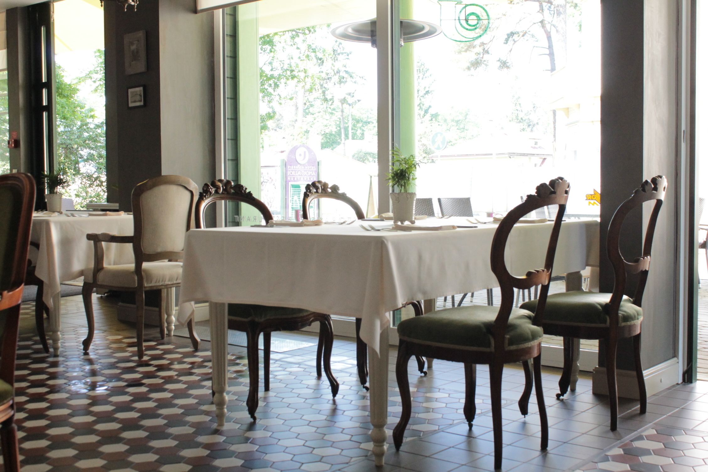 Comedor con una mesa dispuesta para cuatro personas, rodeada de sillas de madera con cojines verdes.