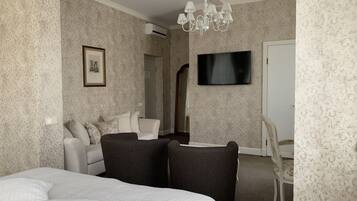 A hotel room with a bed, a sofa, a TV, and a chandelier.