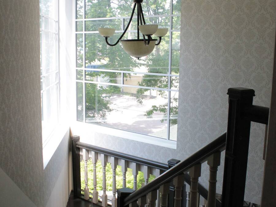 Un escalier avec une rampe en bois menant à un palier doté d’une grande fenêtre.