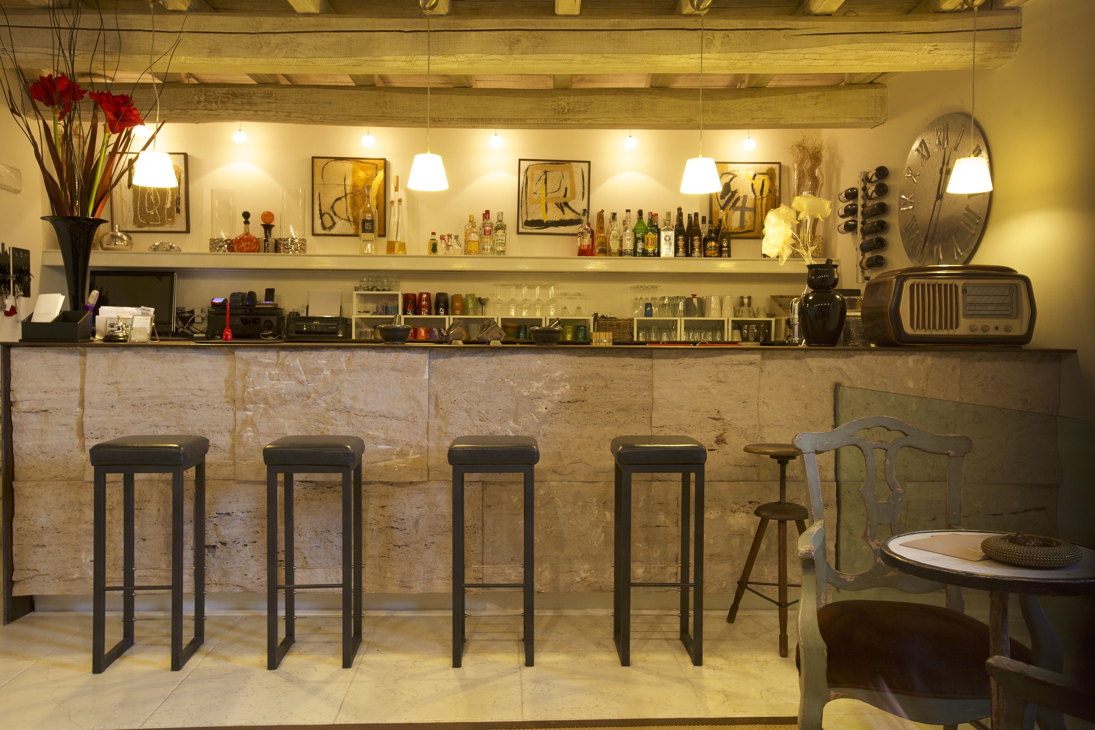 A bar area with stools, a vintage radio, and various bottles and glasses on shelves.