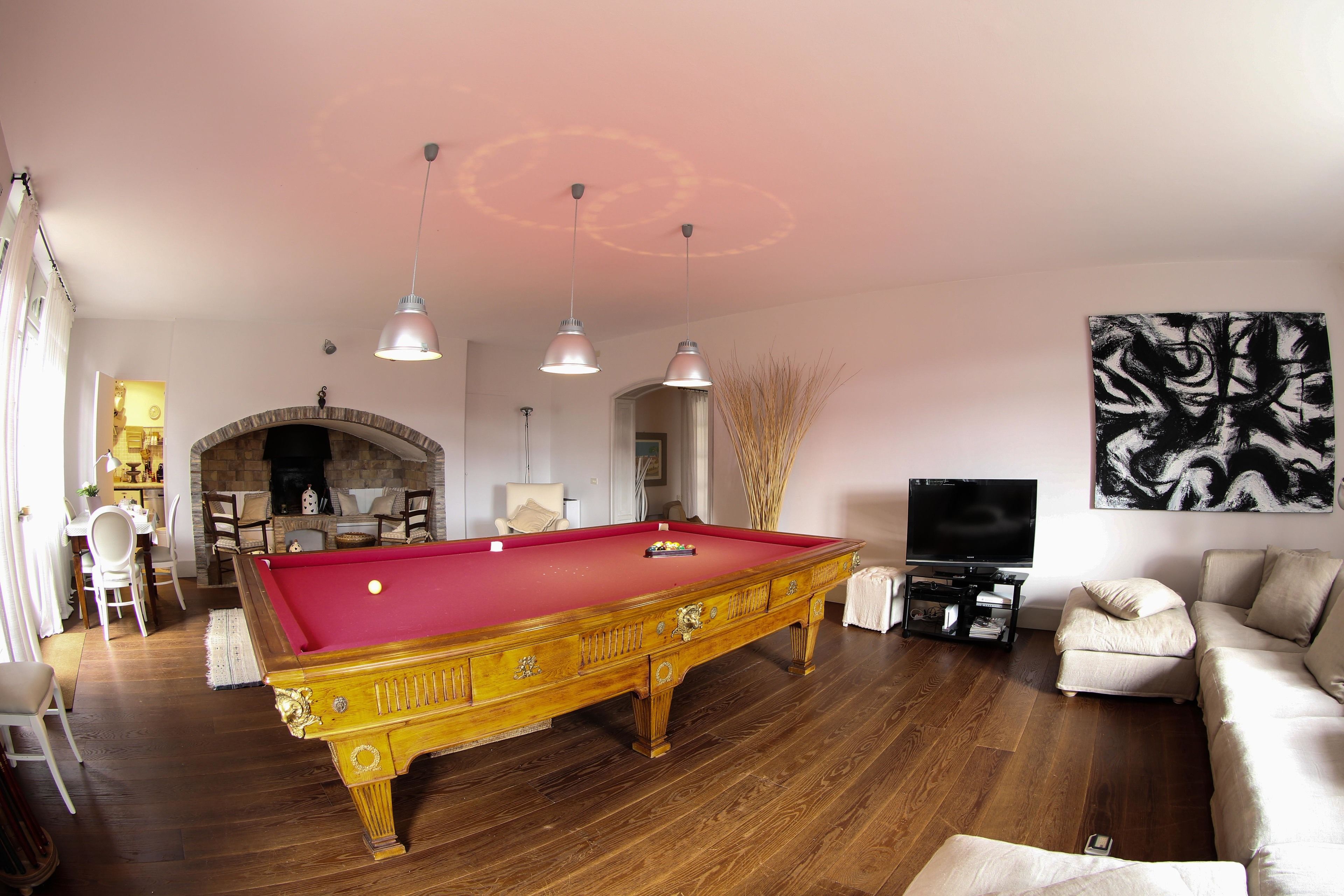 A pool table in a living room with a fireplace, a sofa, and a TV.