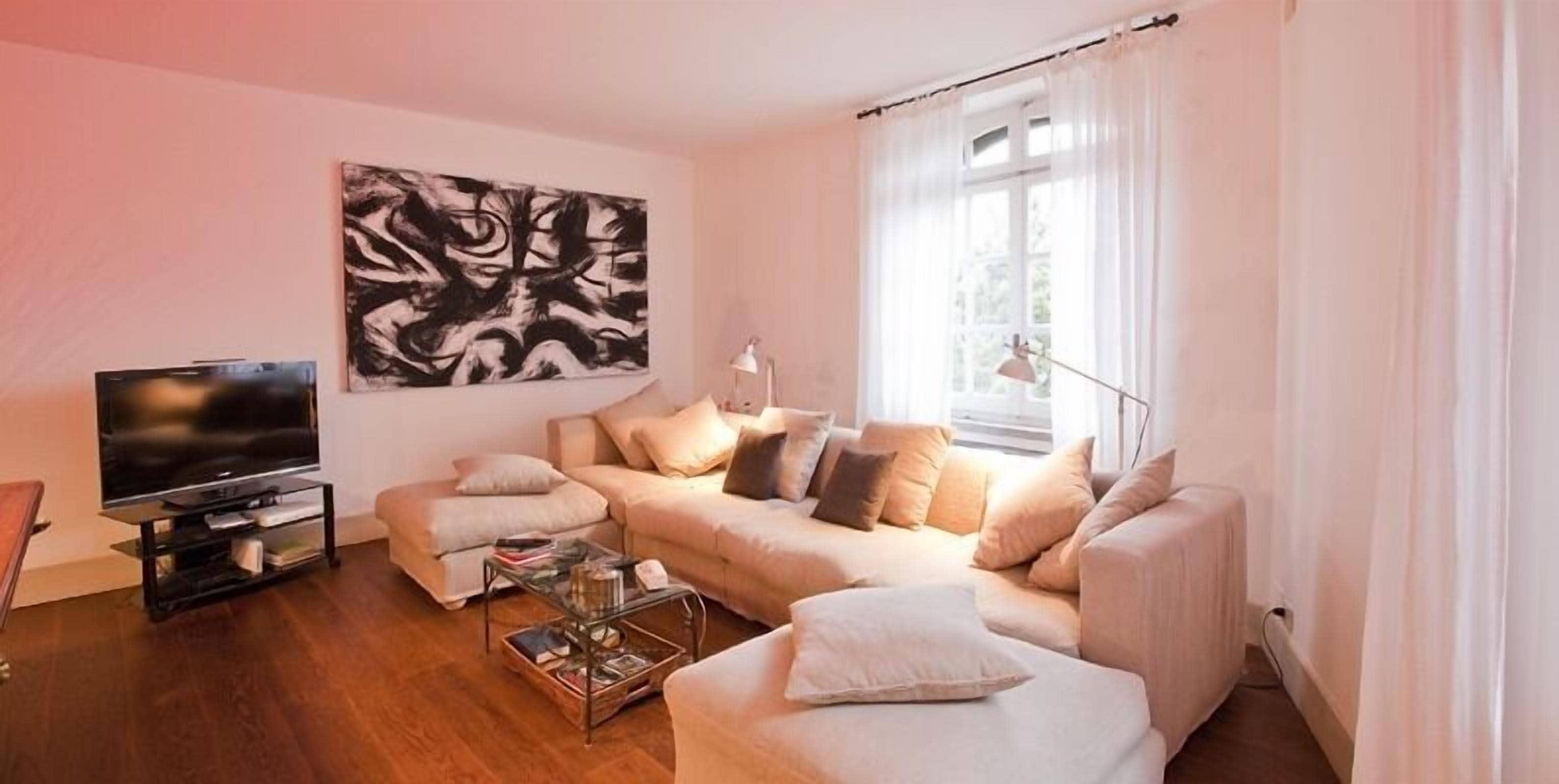 A living room with a sofa set, a TV, and a painting on the wall.