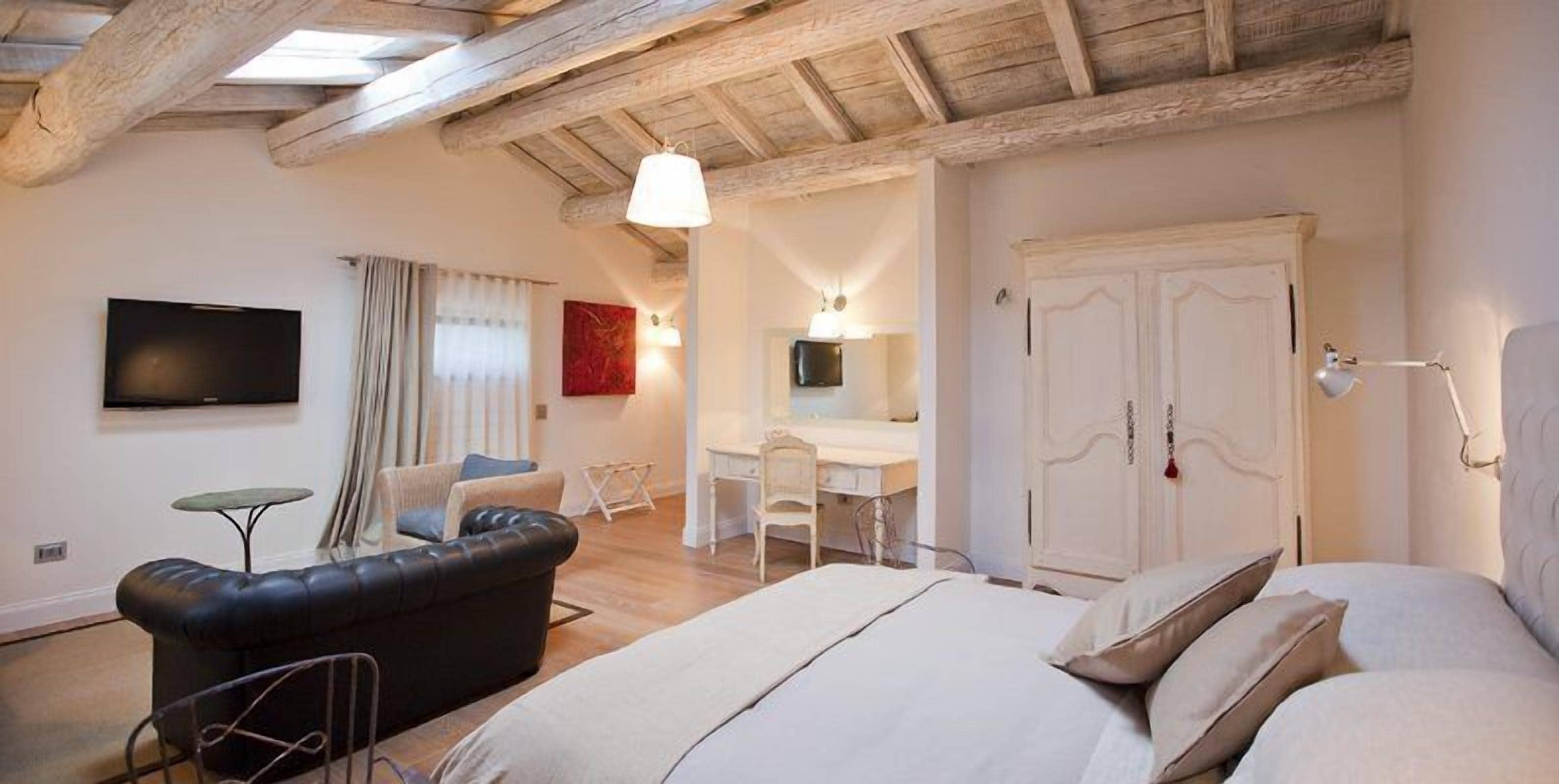 Un dormitorio moderno con una cama grande, un sofá de cuero negro, un escritorio y un armario.