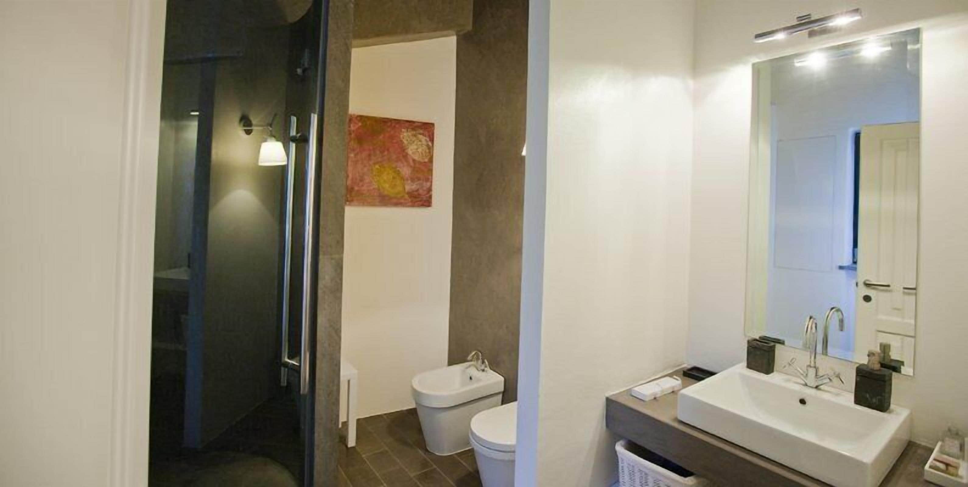 Een moderne badkamer met een douche, toilet en wastafel.