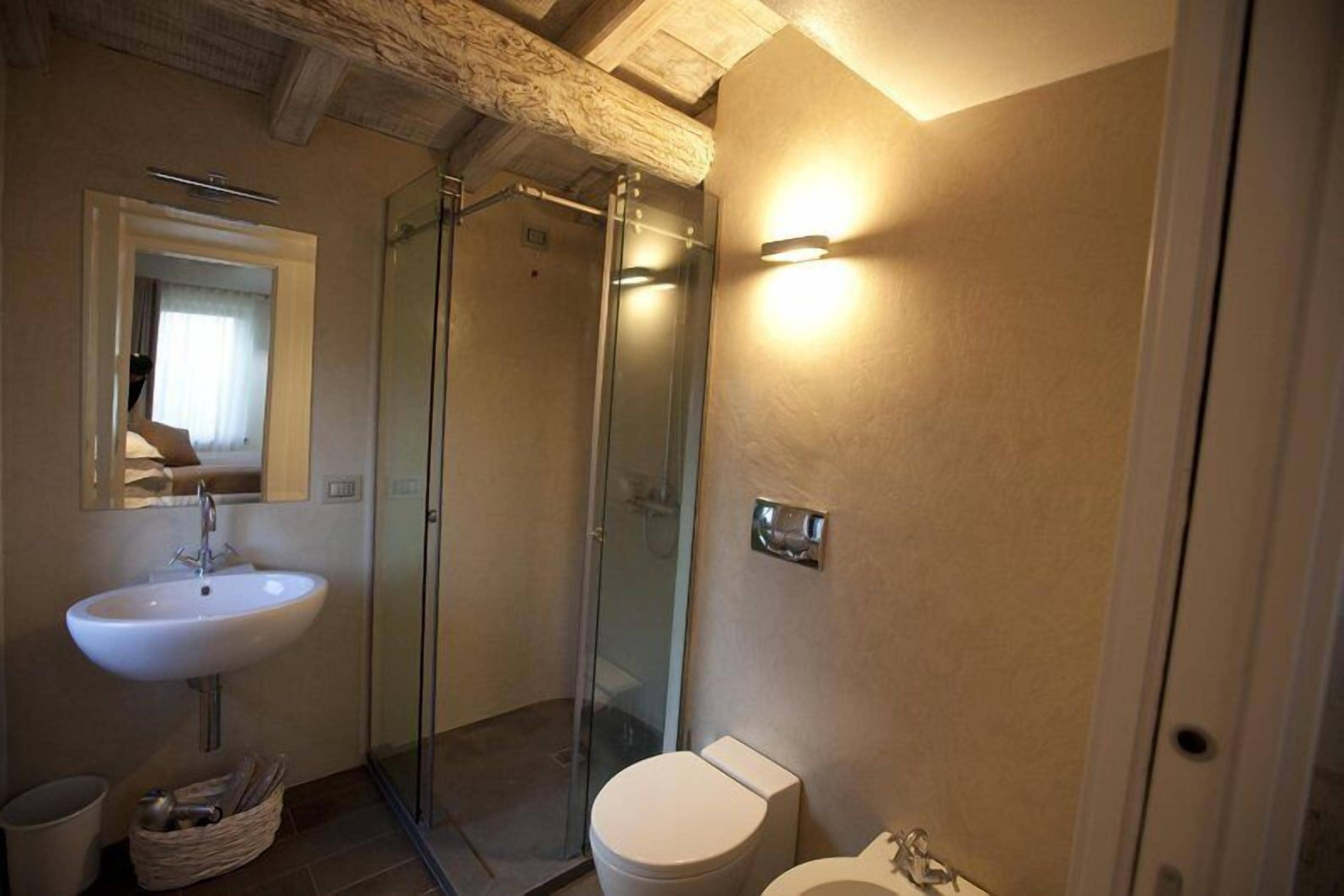 A bathroom with a glass-enclosed shower, a sink, and a toilet.