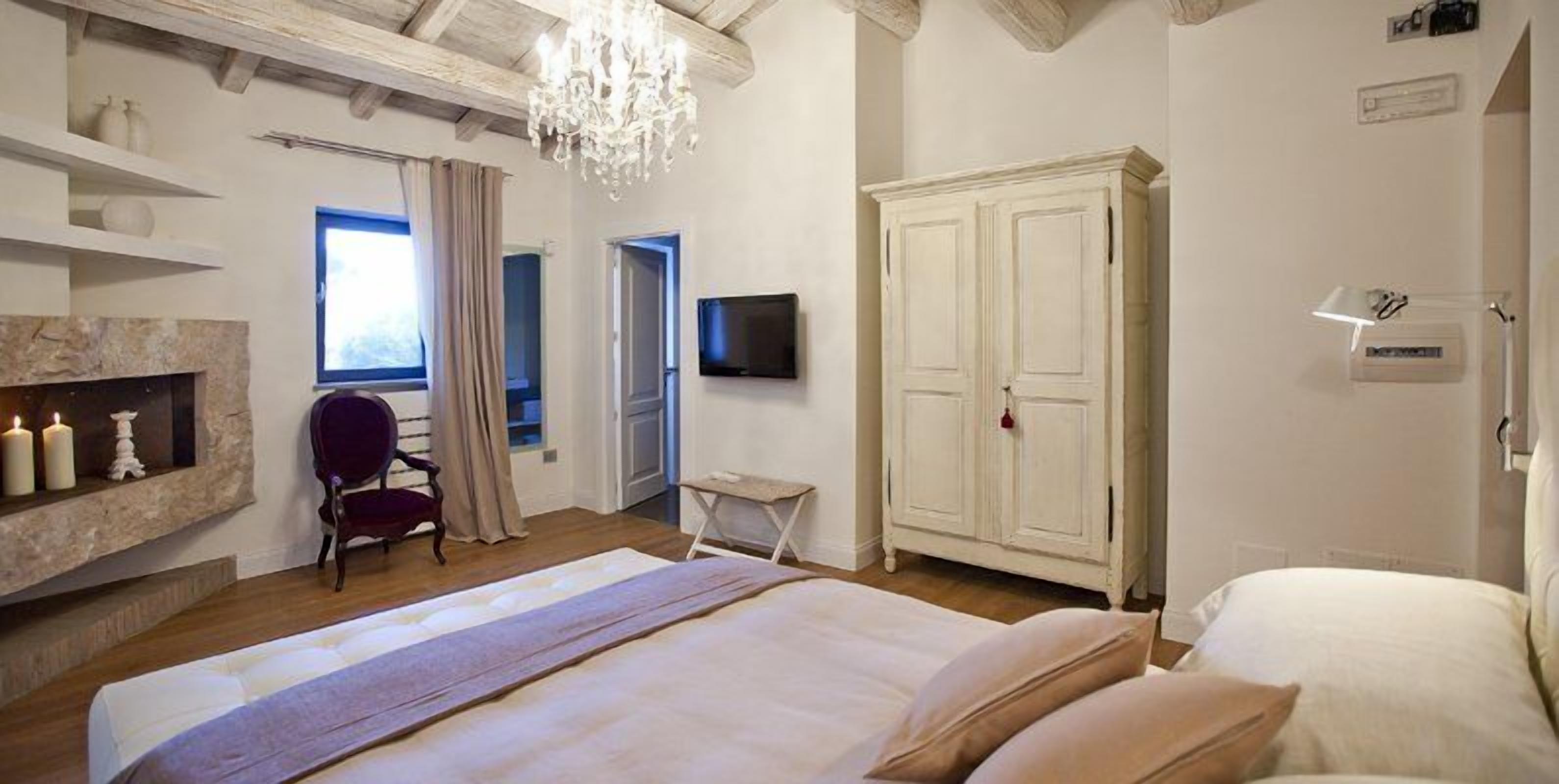 Ein Schlafzimmer mit einem großen Bett, einem Fernseher, einem Kleiderschrank und einer Kandelaber.