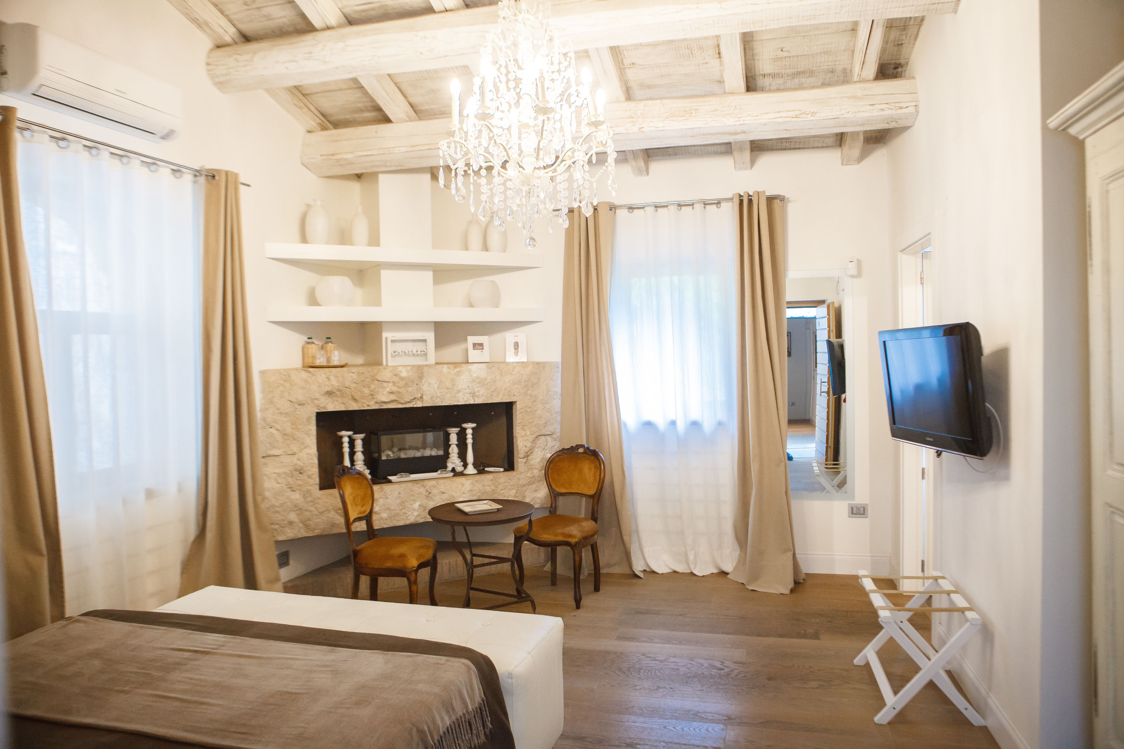 A bedroom with a bed, a fireplace, a television, and a dining area with chairs and a table.