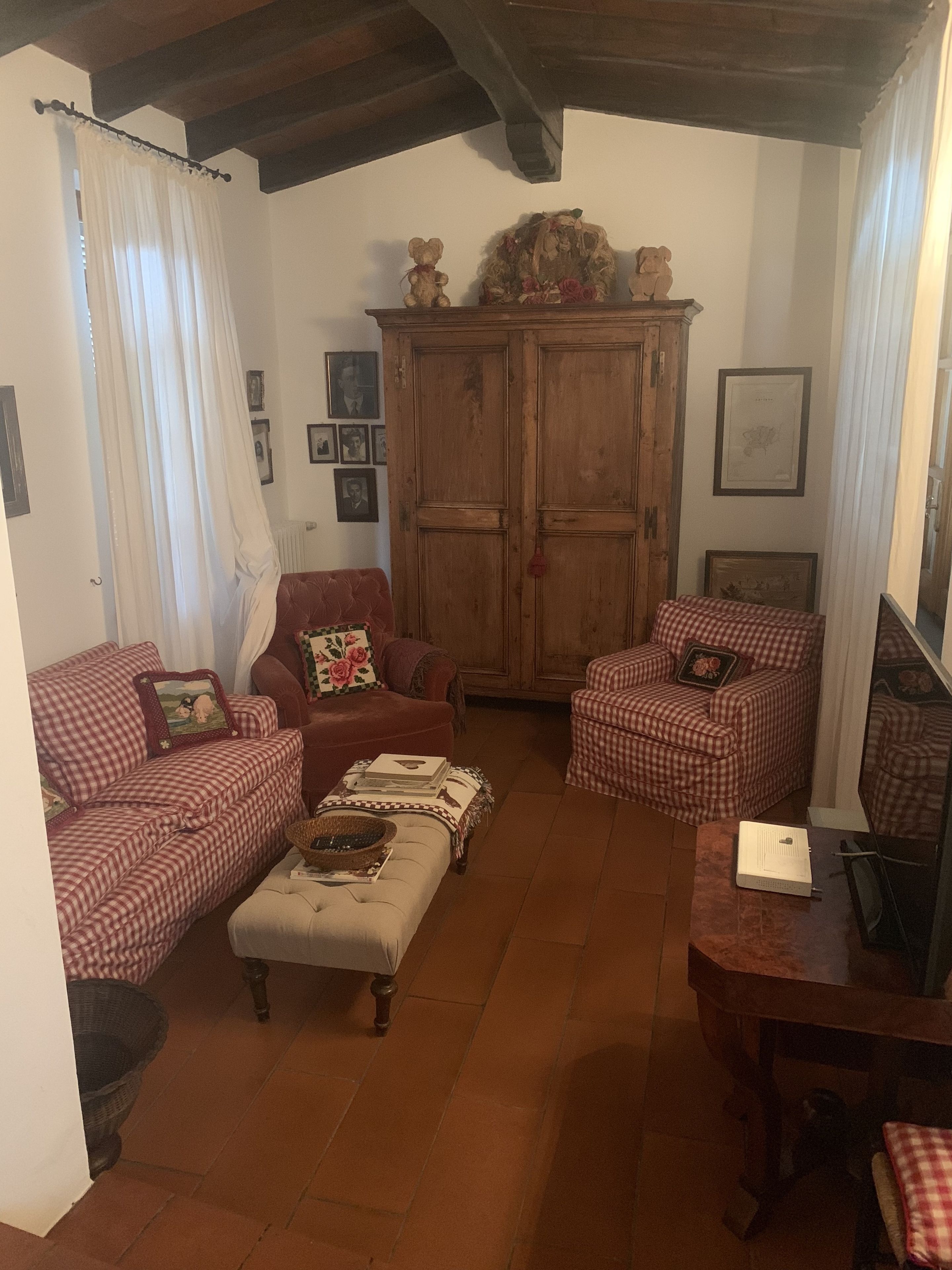 A cozy living room with two checkered sofas, a wooden cabinet, and a television.
