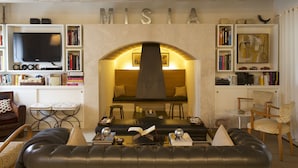 A modern living room with a fireplace, bookshelves, a television, and comfortable seating. - Misia Country Resort (Orvieto)