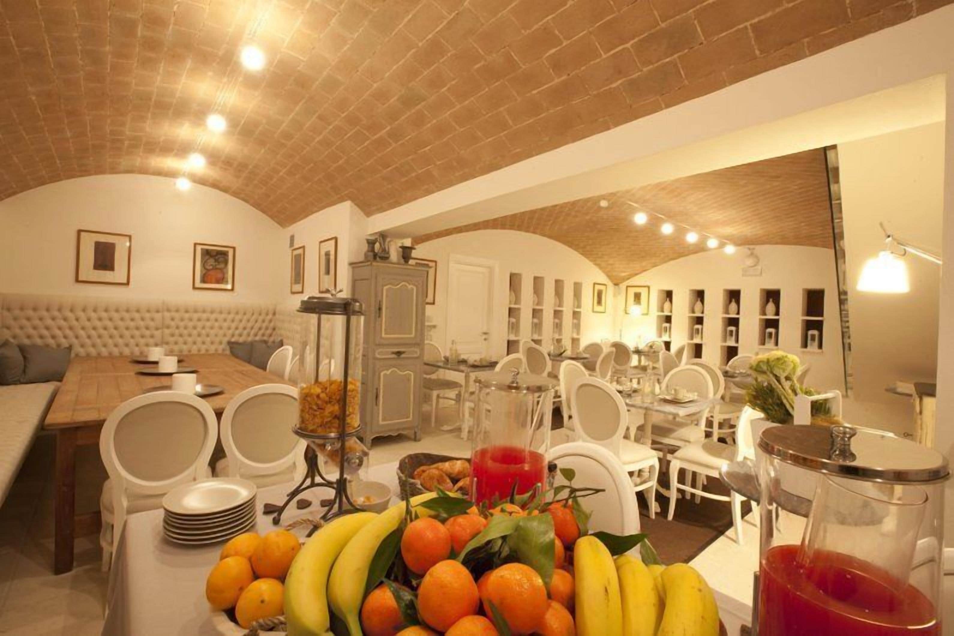 Un espace repas avec un plafond en briques, des meubles blancs et une présentation de fruits.