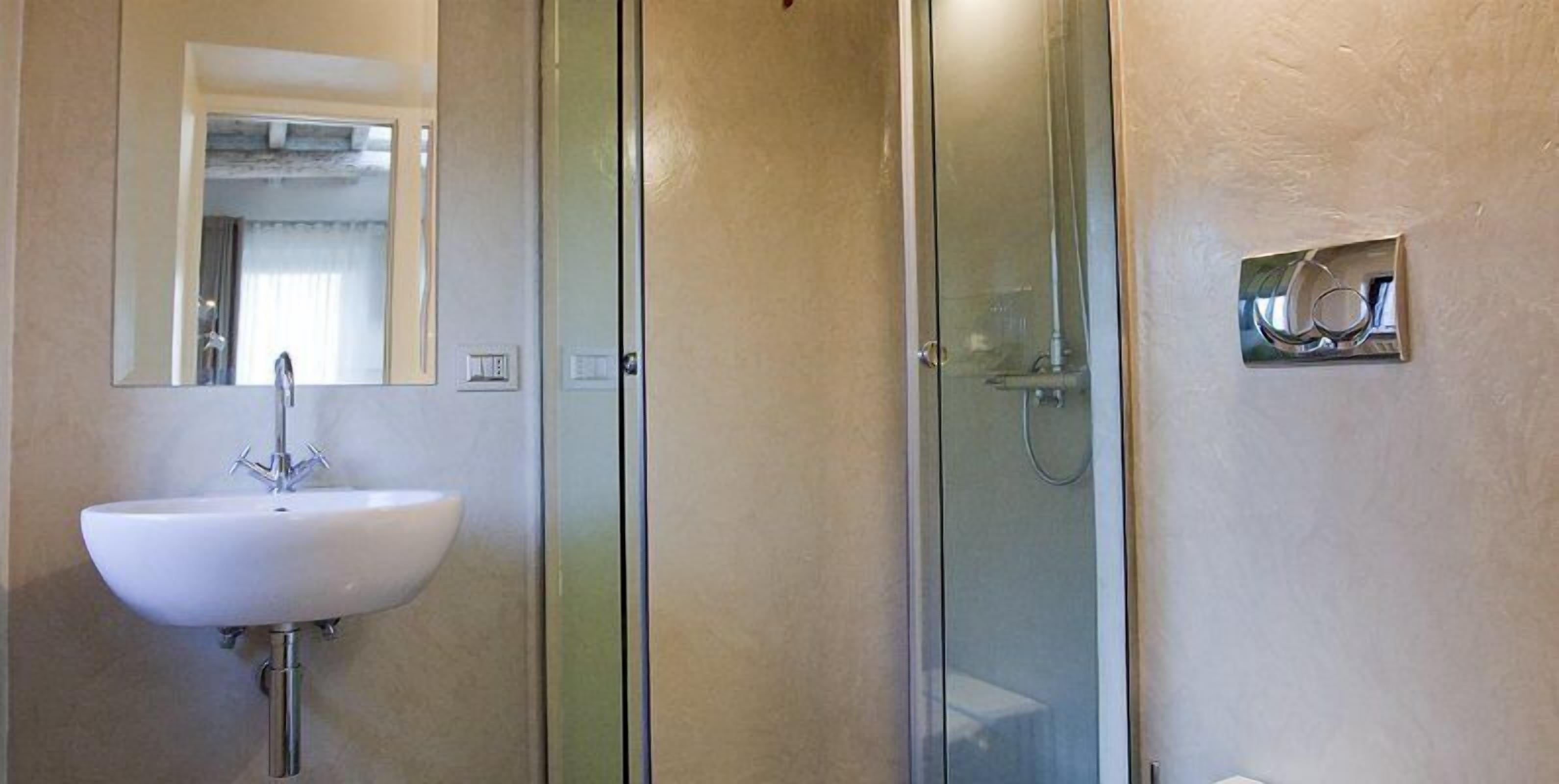 Une salle de bain avec un lavabo blanc, une cabine de douche en verre et un miroir.