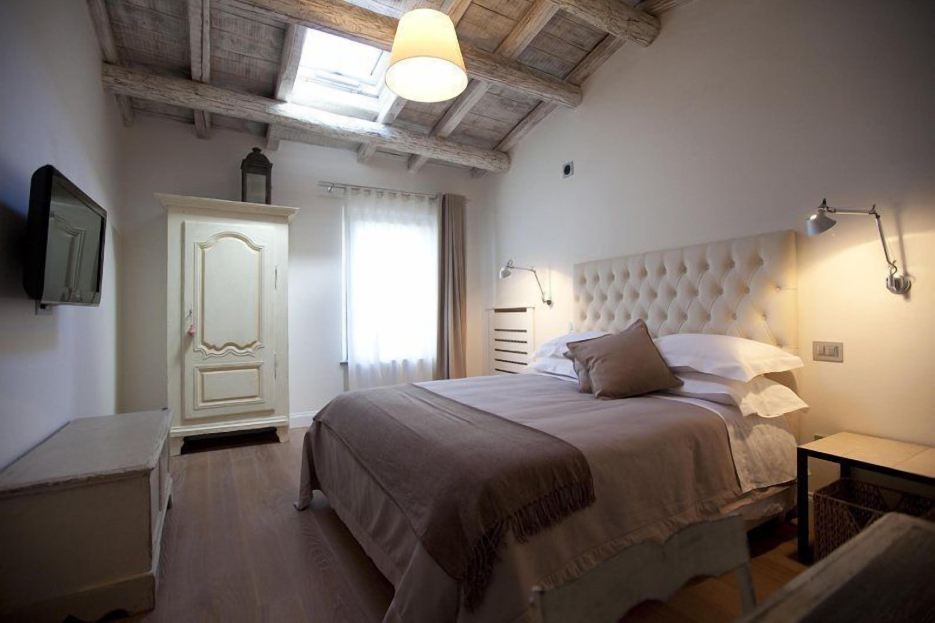 A bedroom with a large bed, a wardrobe, a bedside table, a lamp, and a ceiling light.