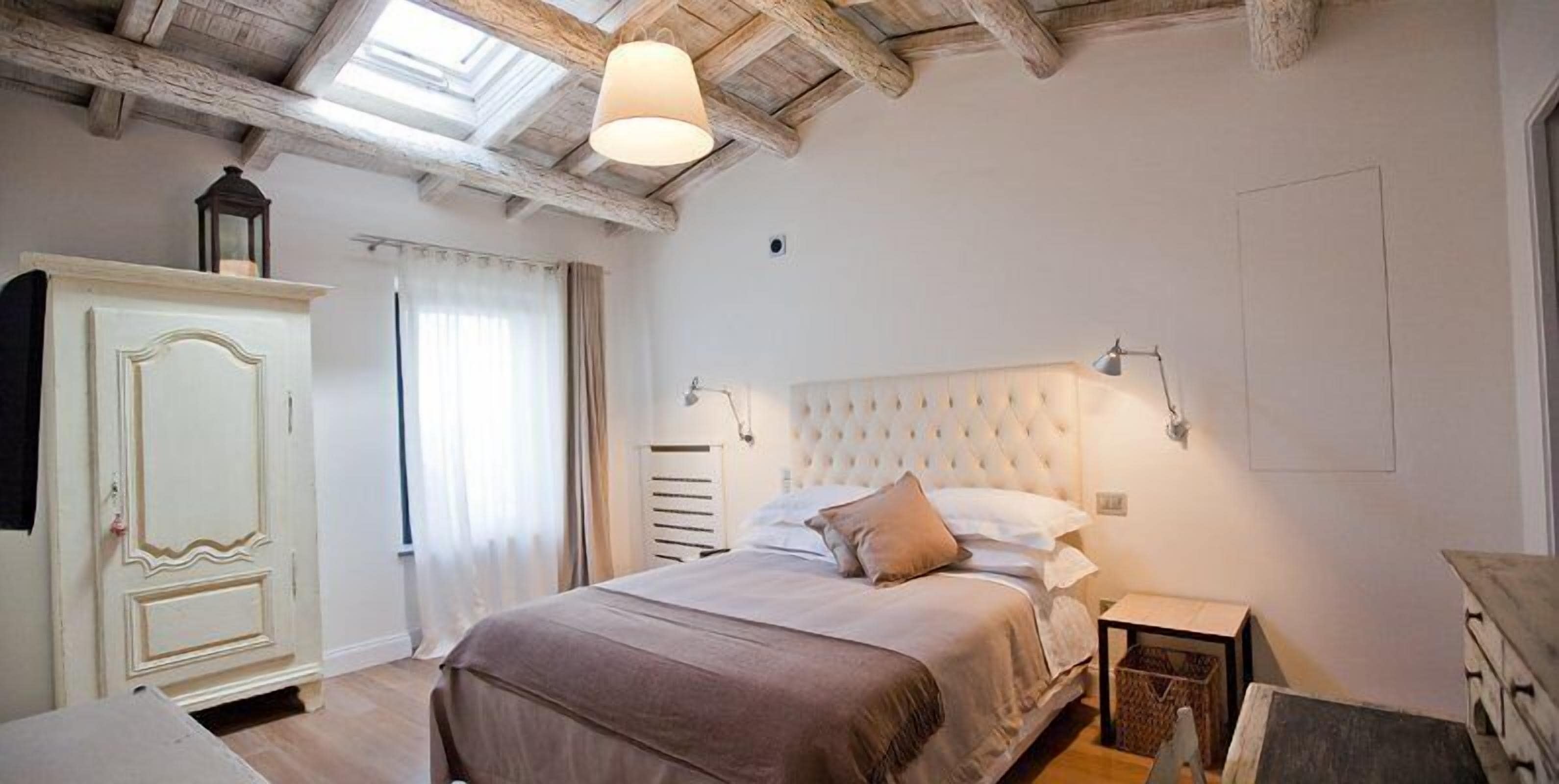 Una camera da letto con un letto, un armadio, un comodino e una finestra a lucernario.