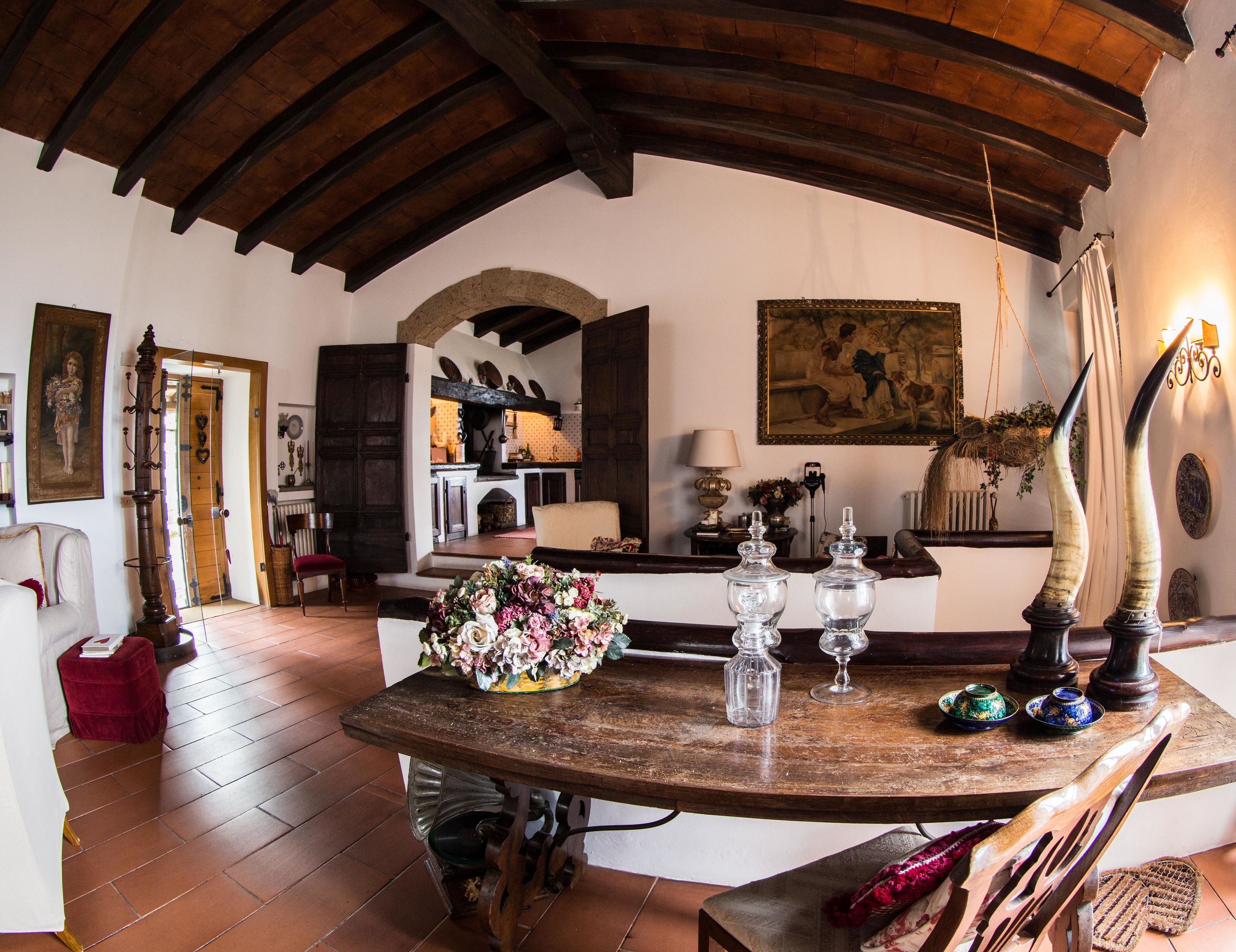 A rustic interior with a wooden table, a vase of flowers, and a fireplace.