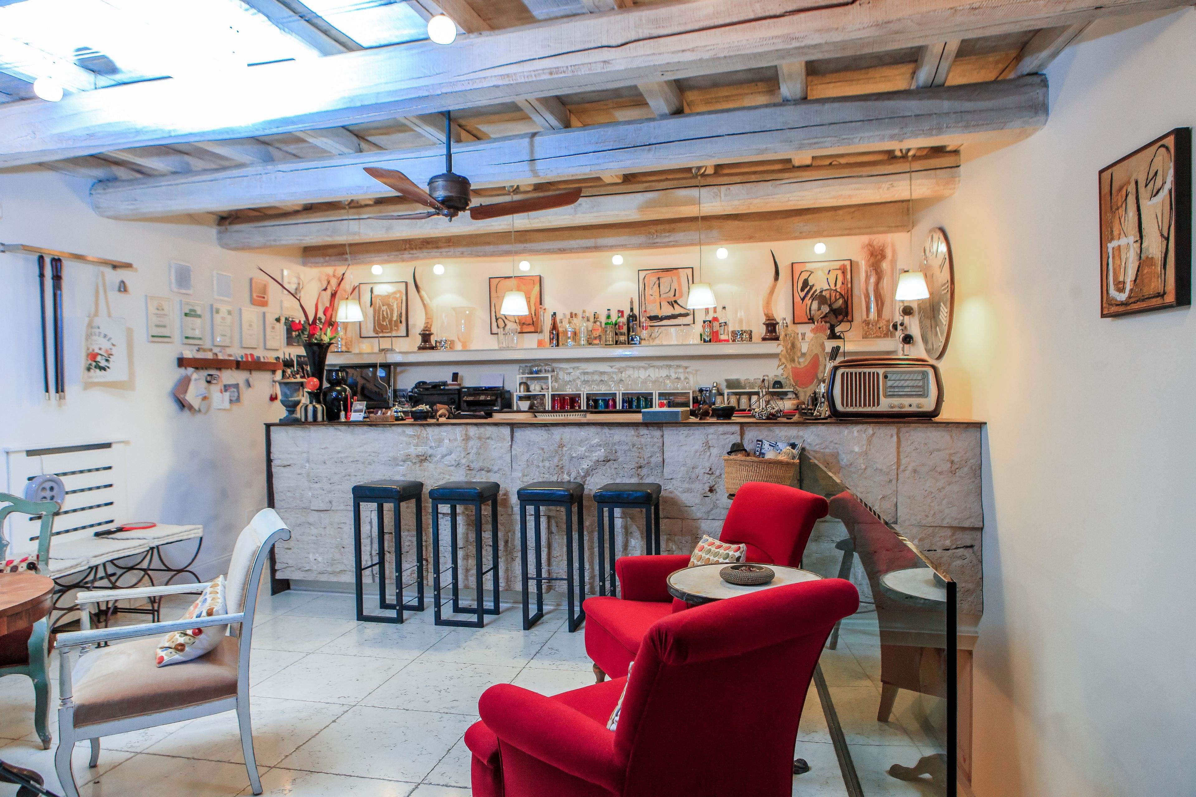Eine gemütliche Bar mit einer Theke, Hockstühlen und roten Sesseln.