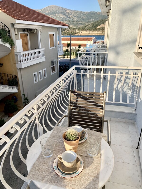 Una terraza con una mesa para dos, un cactus en maceta y vistas al mar y a las montañas.