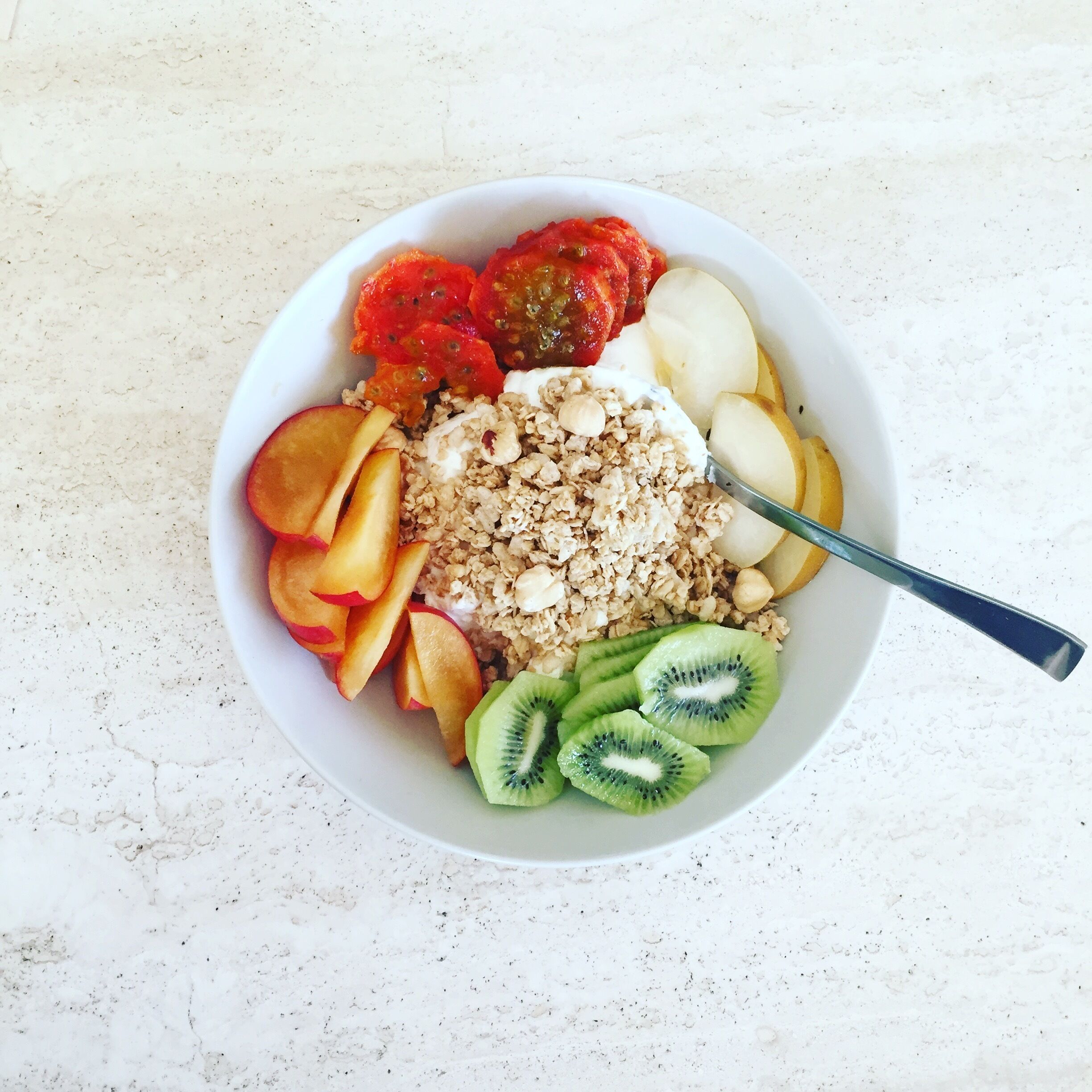 A bowl of cereal with fruits and yogurt.