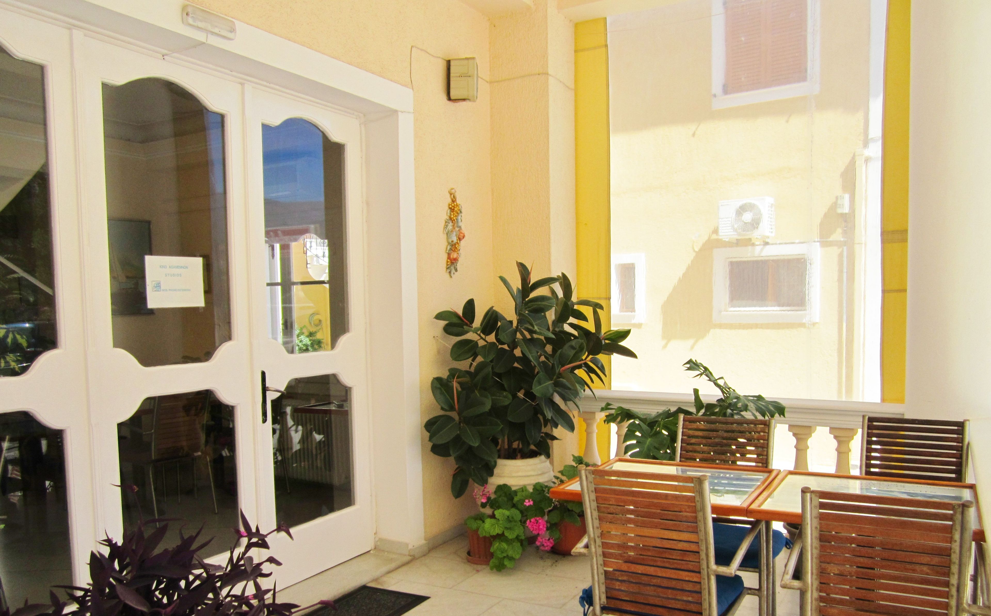 A room with a white door, a potted plant, and a table with chairs.