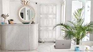 Une salle de bain moderne avec un meuble-lavabo en marbre, un miroir rond doté d’un cadre décoratif, une cabine de douche et une plante en pot.