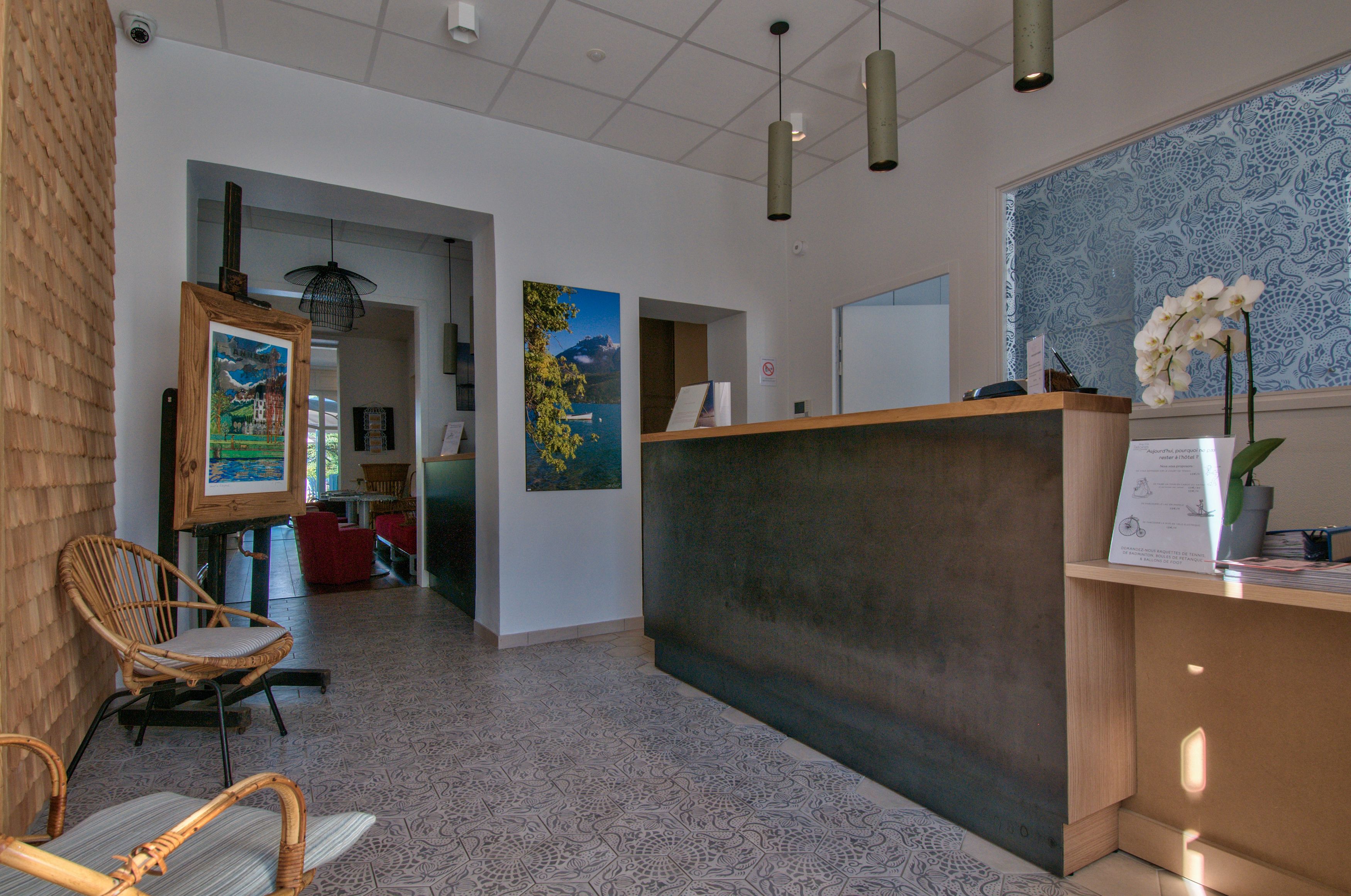 A reception area with a wooden reception desk, a wicker chair, and artwork on the walls.