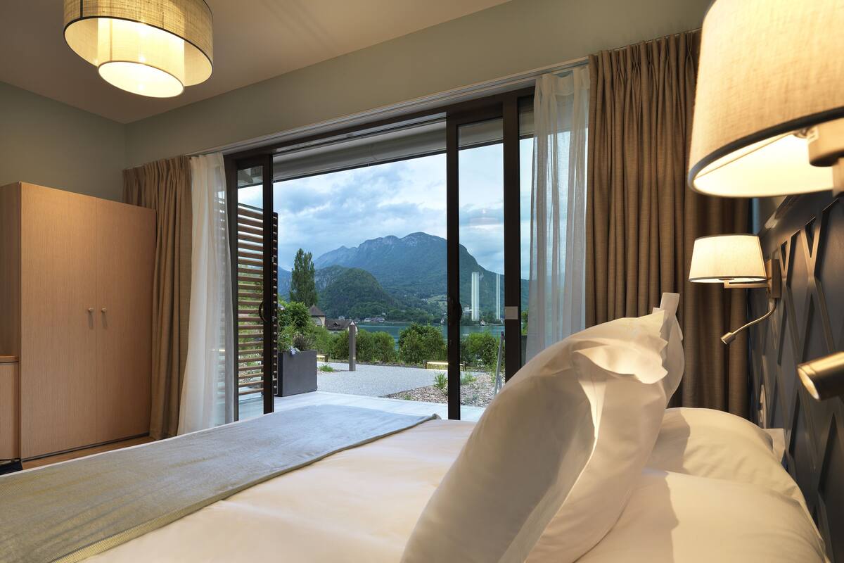 Une chambre d’hôtel avec un lit, une armoire et une vue sur les montagnes et un lac.