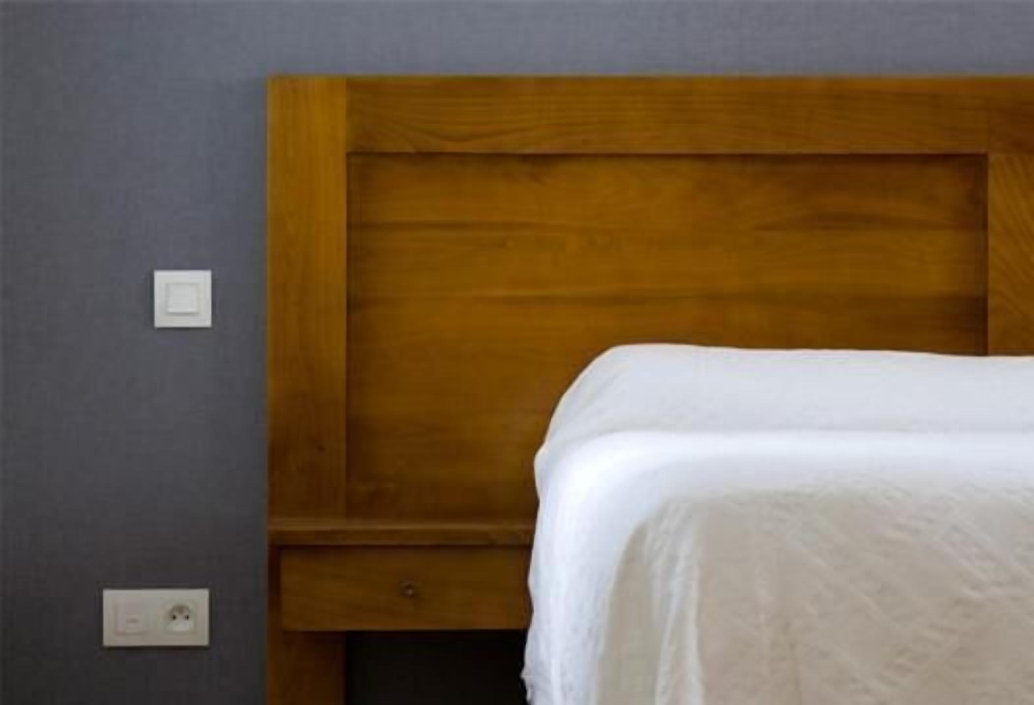 A single bed with a wooden headboard in a room with gray walls.