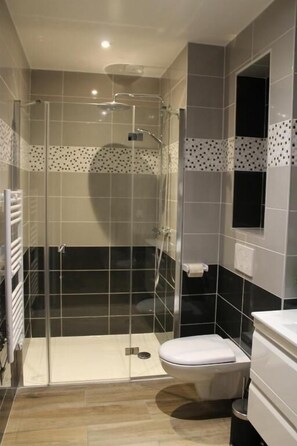 A modern bathroom with a glass-enclosed shower, a toilet, and a sink. - Auberge Etchoinia (Lasse)