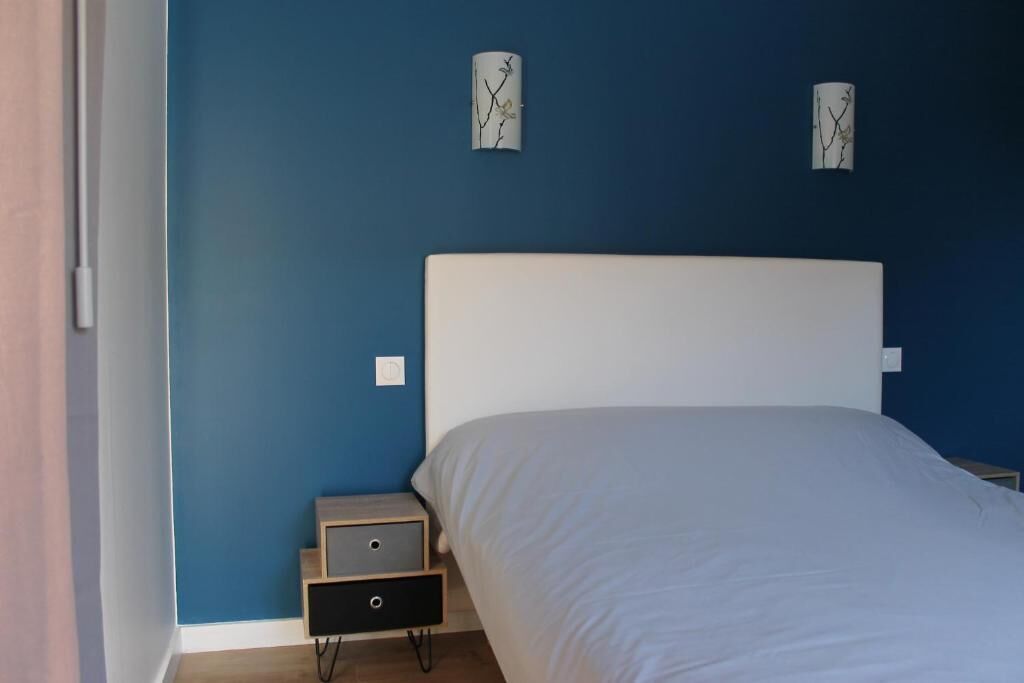 Une chambre à coucher comprenant un lit, une table de chevet et une commode.