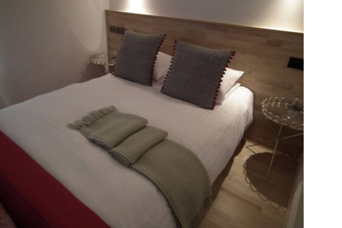 A neatly made bed with a white duvet, two grey pillows, and a beige throw blanket.