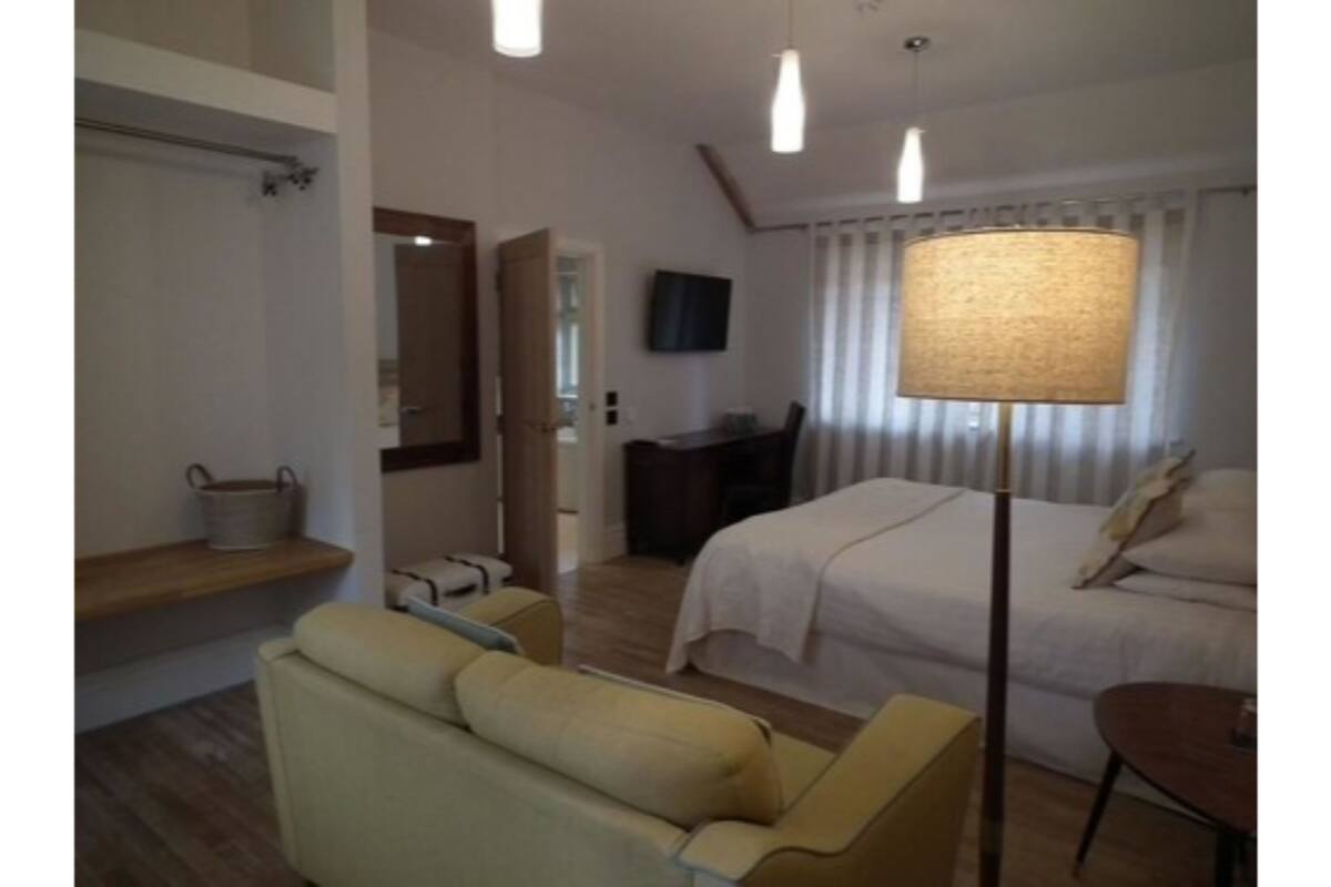 A hotel room with a bed, a desk, a chair, a lamp, and a mirror.